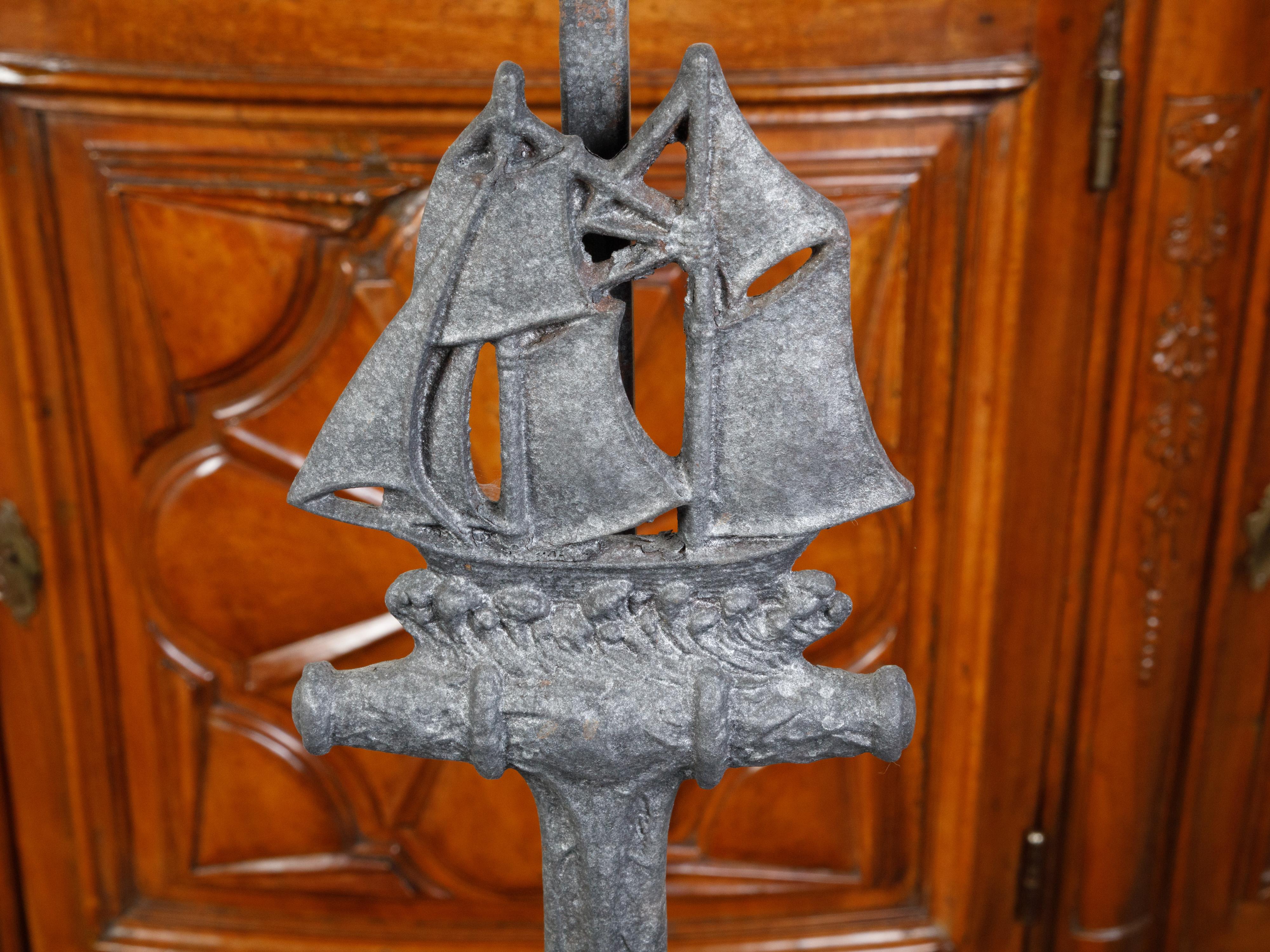 A pair of iron vintage table lamps from the mid 20th century, depicting anchors and sailboats. Created during the second quarter of the 20th century, this pair of iron table lamps, wired for the US, attracts our attention with its anchors mounted on