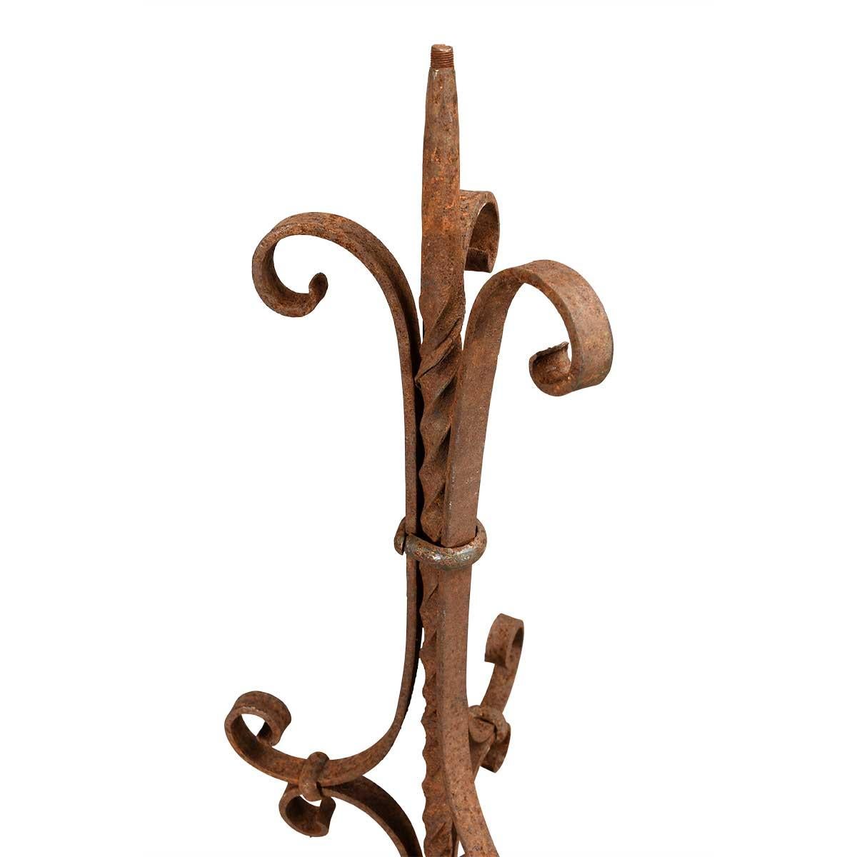 Paire de torchères en fer forgé de forme sinueuse avec un poteau central torsadé et reposant sur une base tripartite. Belle surface.