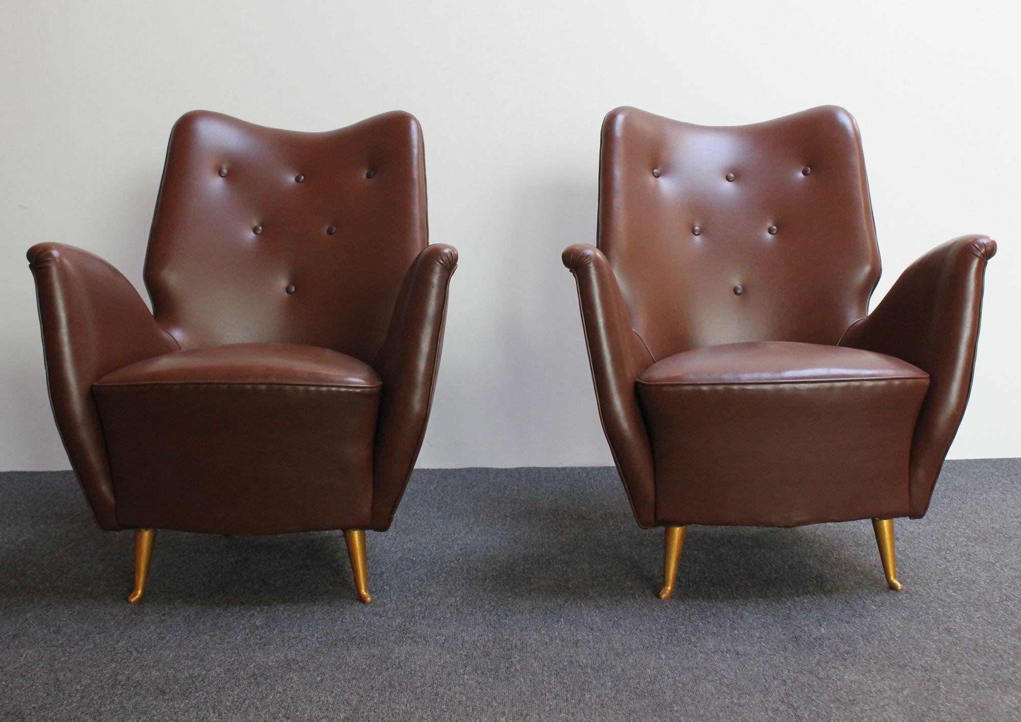 Low and petite Isa Bergamo arm/club chairs attributed to Gio Ponti characterized by pronounced/exaggeratedly sculpted arms in chocolate vinyl with button tufted details (ca. 1950s, Italy).
Original spring construction present with the frame