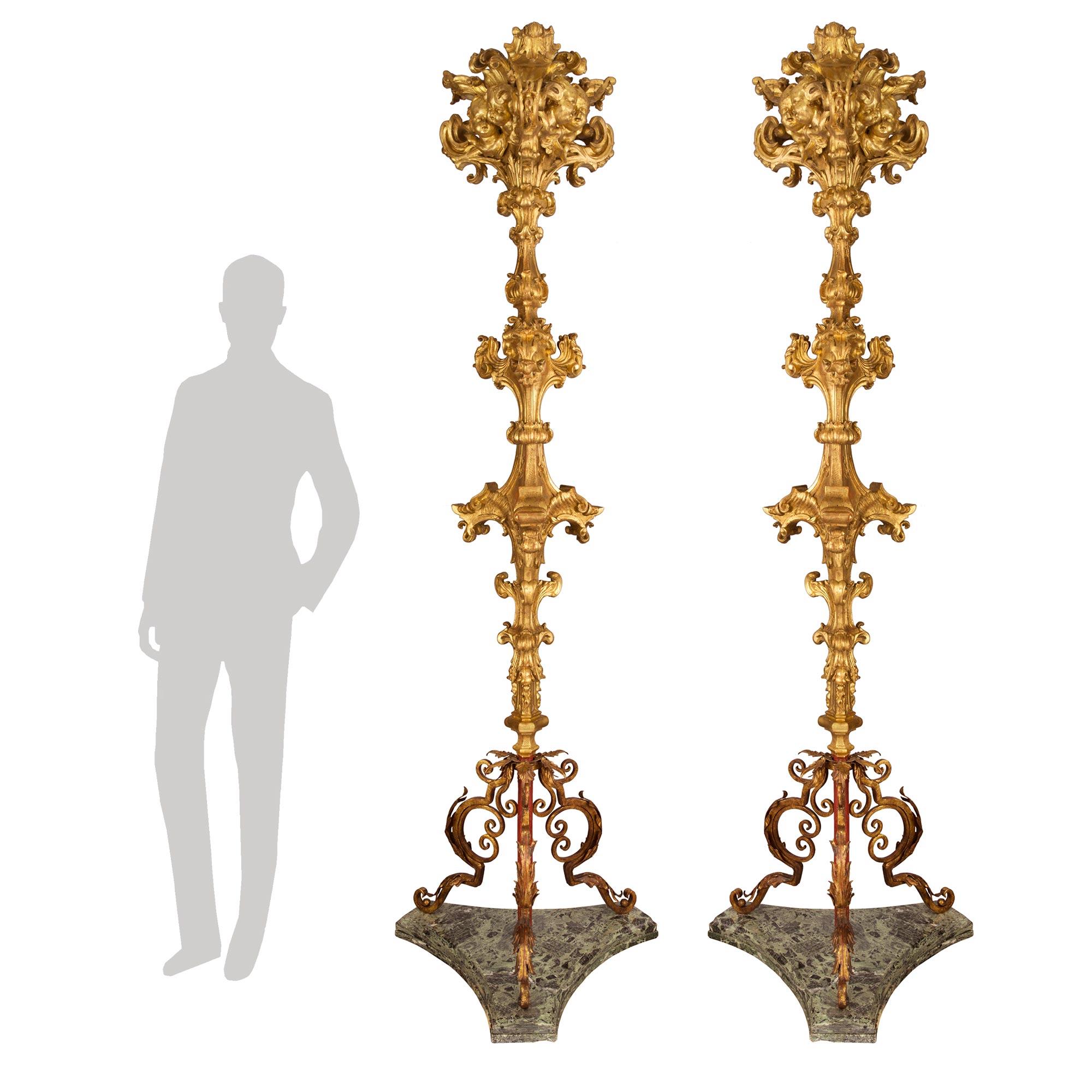 Une paire sensationnelle et rare de lampadaires torchères en bois doré, métal doré et marbre Verde Antico, d'époque baroque du XVIIe siècle. Chaque lampadaire de grande taille est surélevé par des bases triangulaires en marbre Verde Antico du XIXe