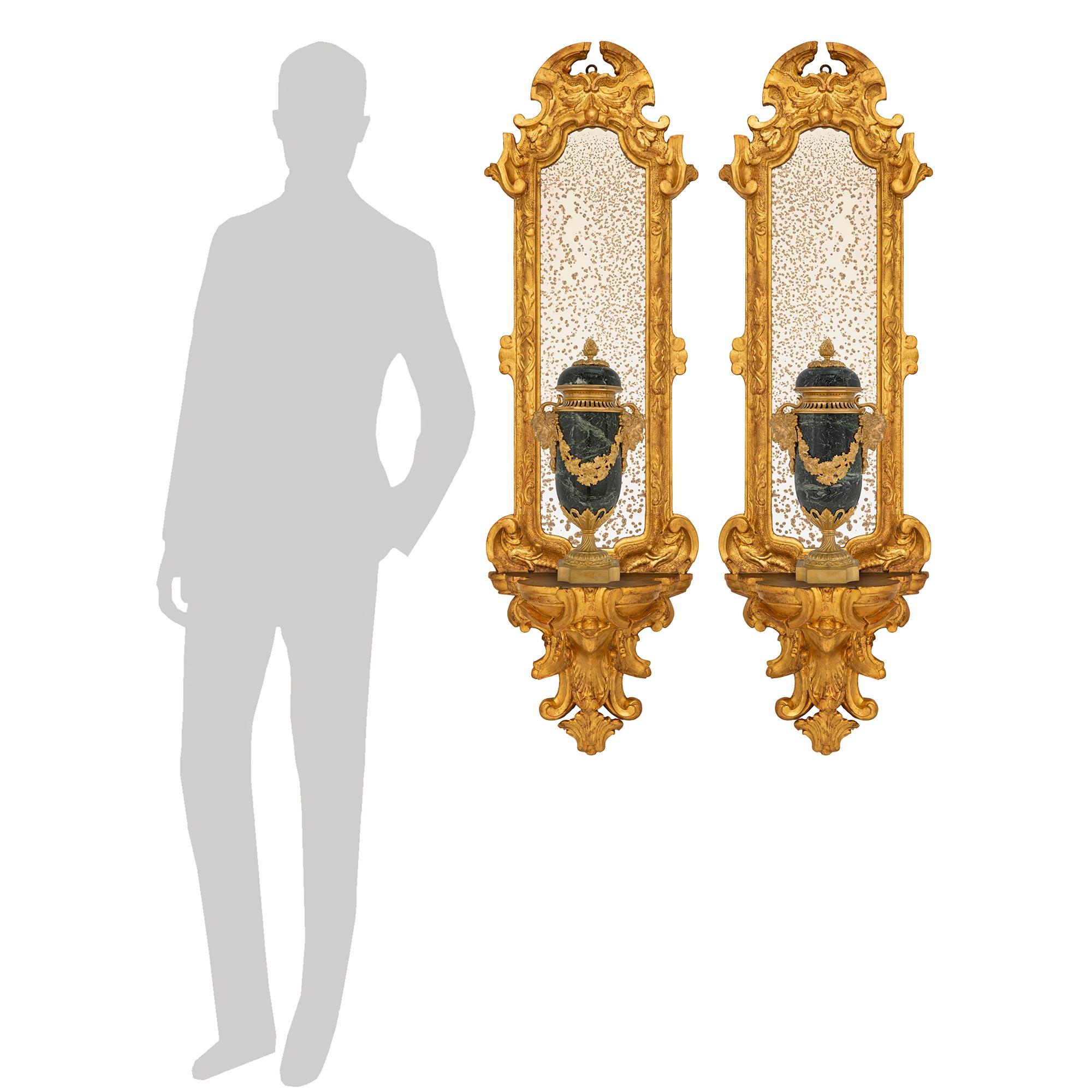 A stunning and finely detailed pair of Italian 17th century Baroque period Giltwood mirrored wall brackets. Each wall bracket is centered by an impressive richly carved bottom foliate display shelf with elegant scrolled designs. Above the display