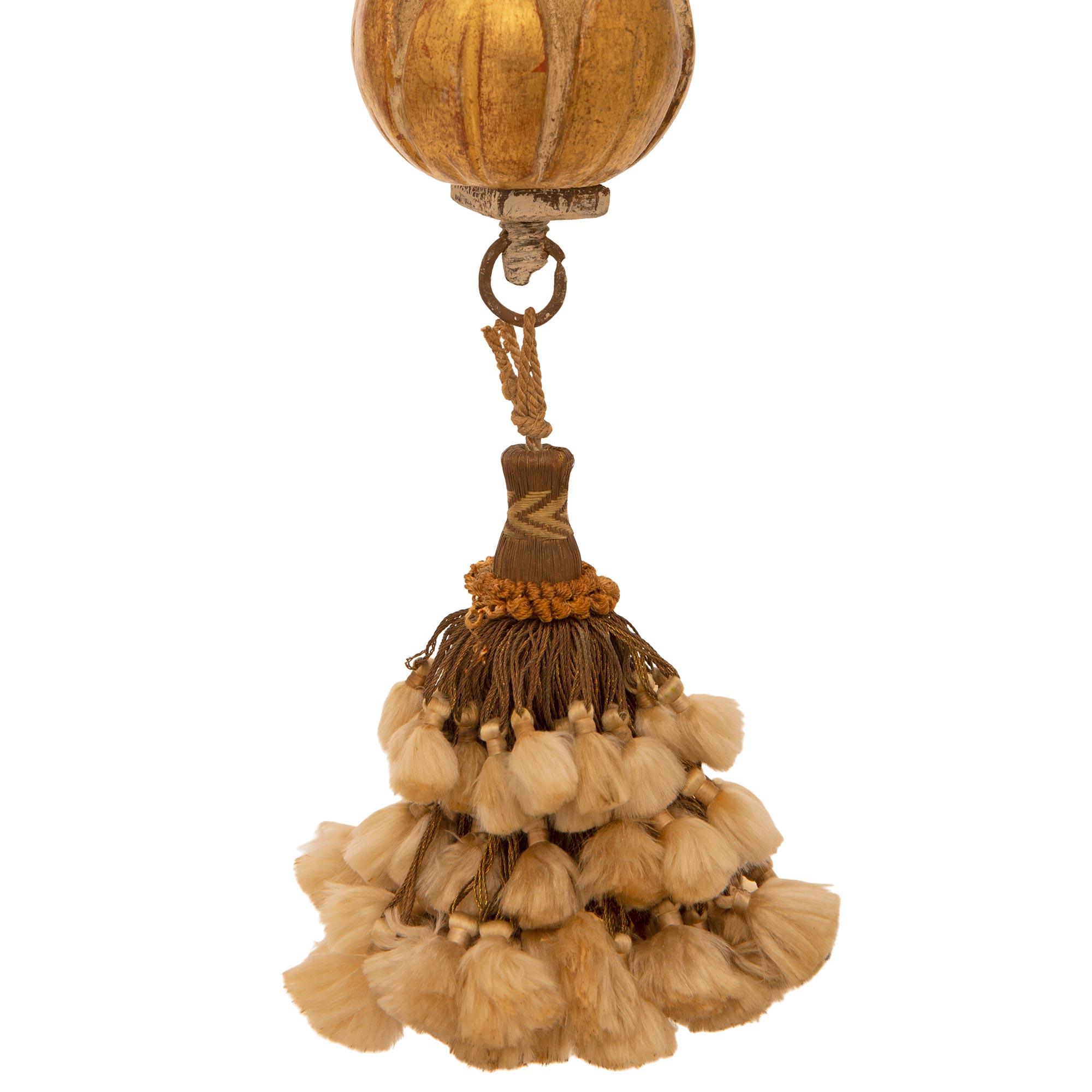An extremely decorative and unique pair of Italian late 17th century Louis XIV Period patinated wood and Giltwood chandeliers. Each beautiful six arm six light chandelier is centered by a bouquet of silk tassels hanging below a foliate decorated