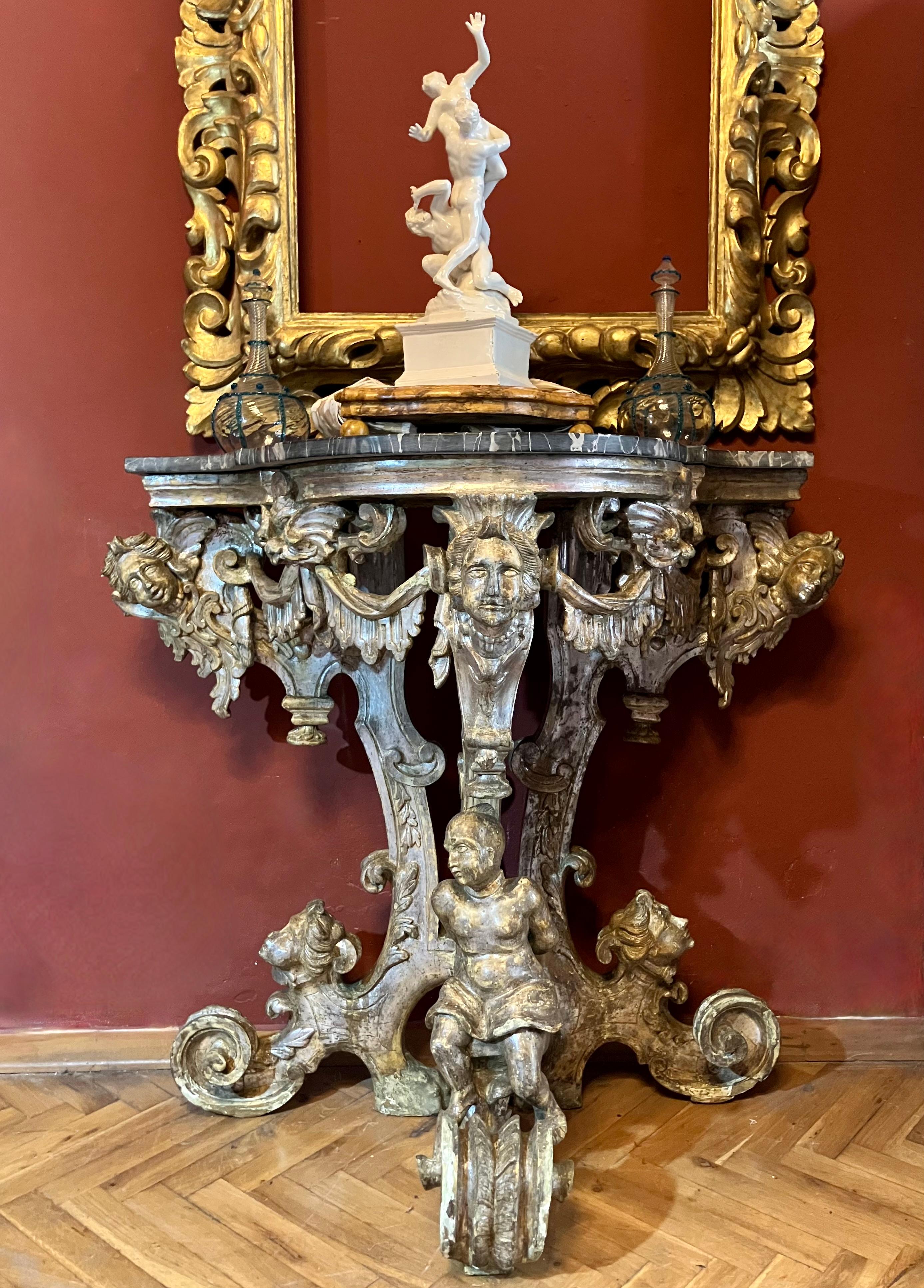 Extraordinaria pareja de consolas barrocas italianas del siglo XVII, que destacan por su gran calidad escultórica y su suntuosa decoración teatral.
Cada consola presenta una exuberante base tallada en madera dorada con acabado de meca plateada,