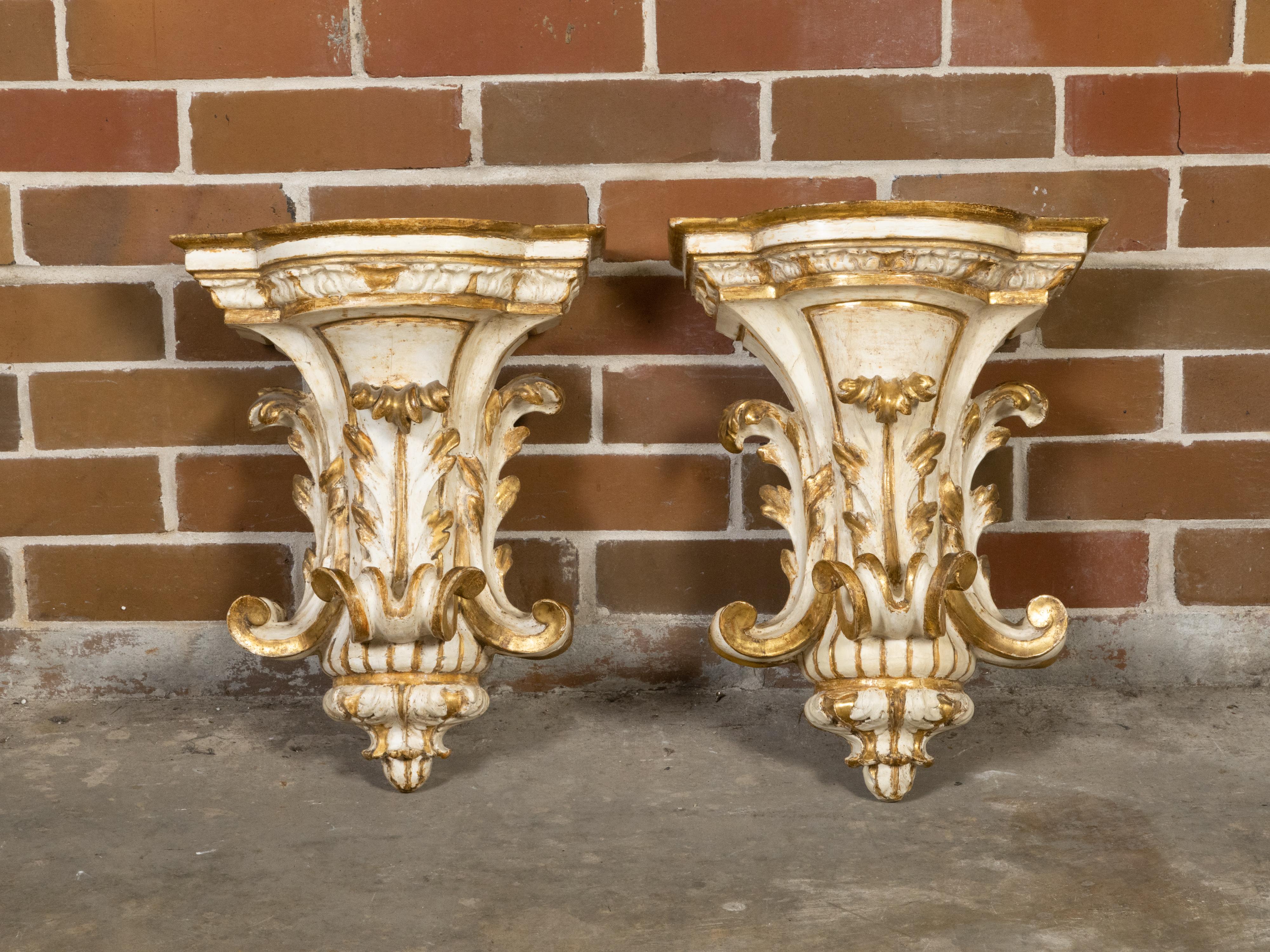 A pair of Italian parcel-gilt and painted wooden brackets from the early 19th century, with carved acanthus leaves and nice patina. Created in Italy during the early years of the 19th century, this pair of wall brackets captures our attention with