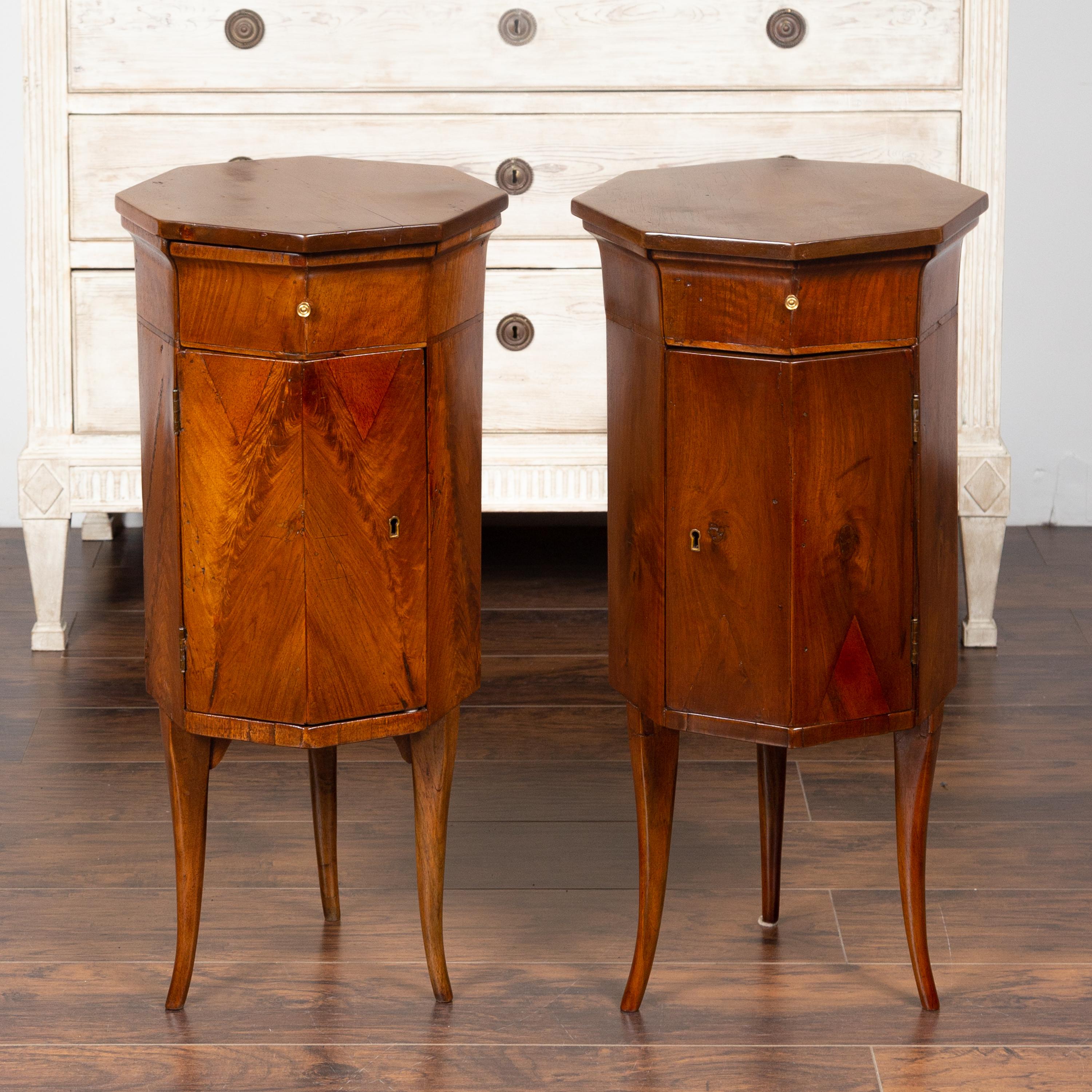 A pair of Italian walnut side tables from the early 19th century, with octagonal tops, drawers and doors. Created in Italy during the early years of the 19th century, each of this pair of walnut side tables features an octagonal top sitting above a
