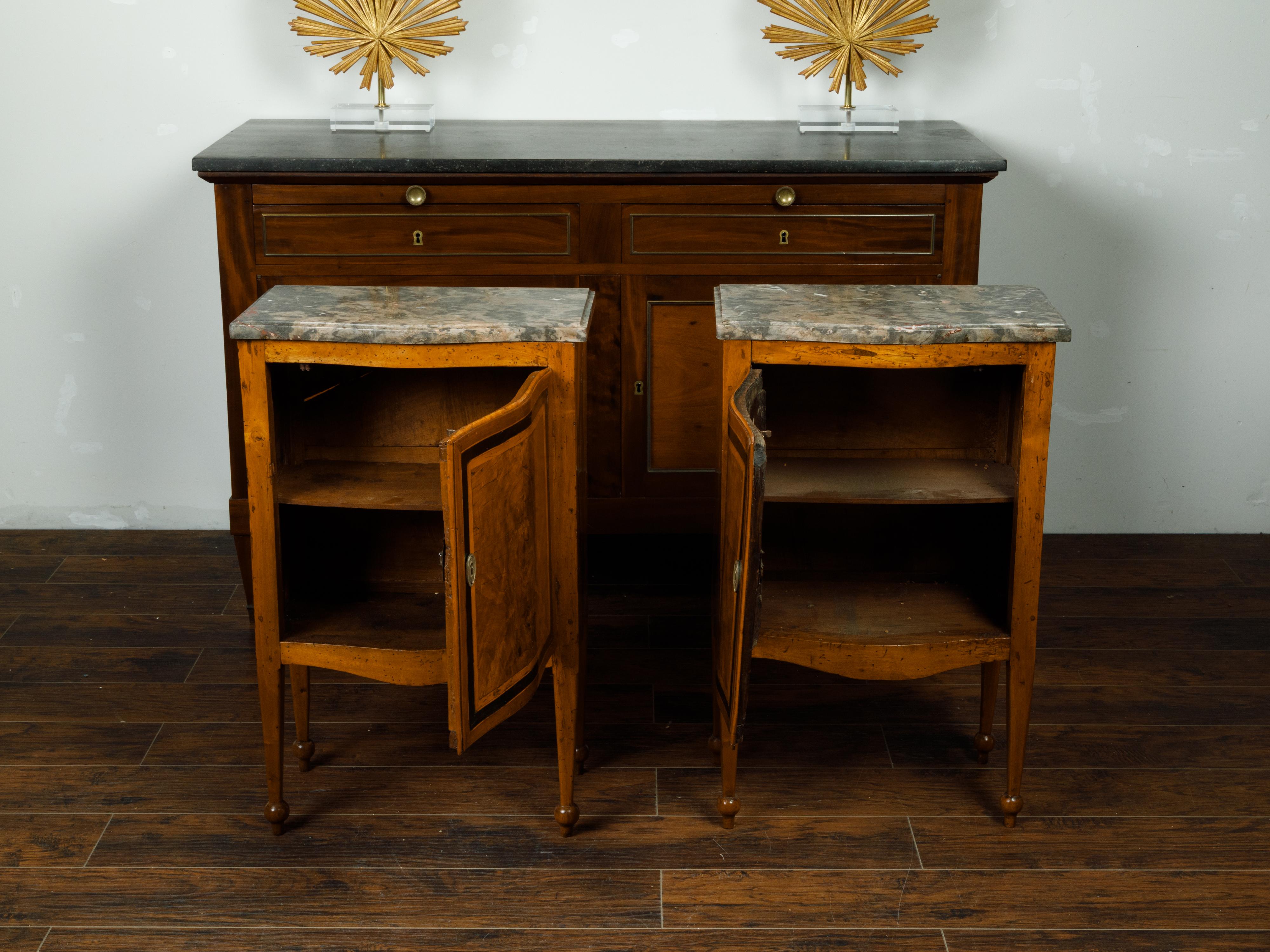 A pair of Italian walnut tables from the mid 19th century, with variegated marble top, single door and butterfly veneer. Created in Italy during the second quarter of the 19th century, each of this pair of walnut tables features a rectangular marble