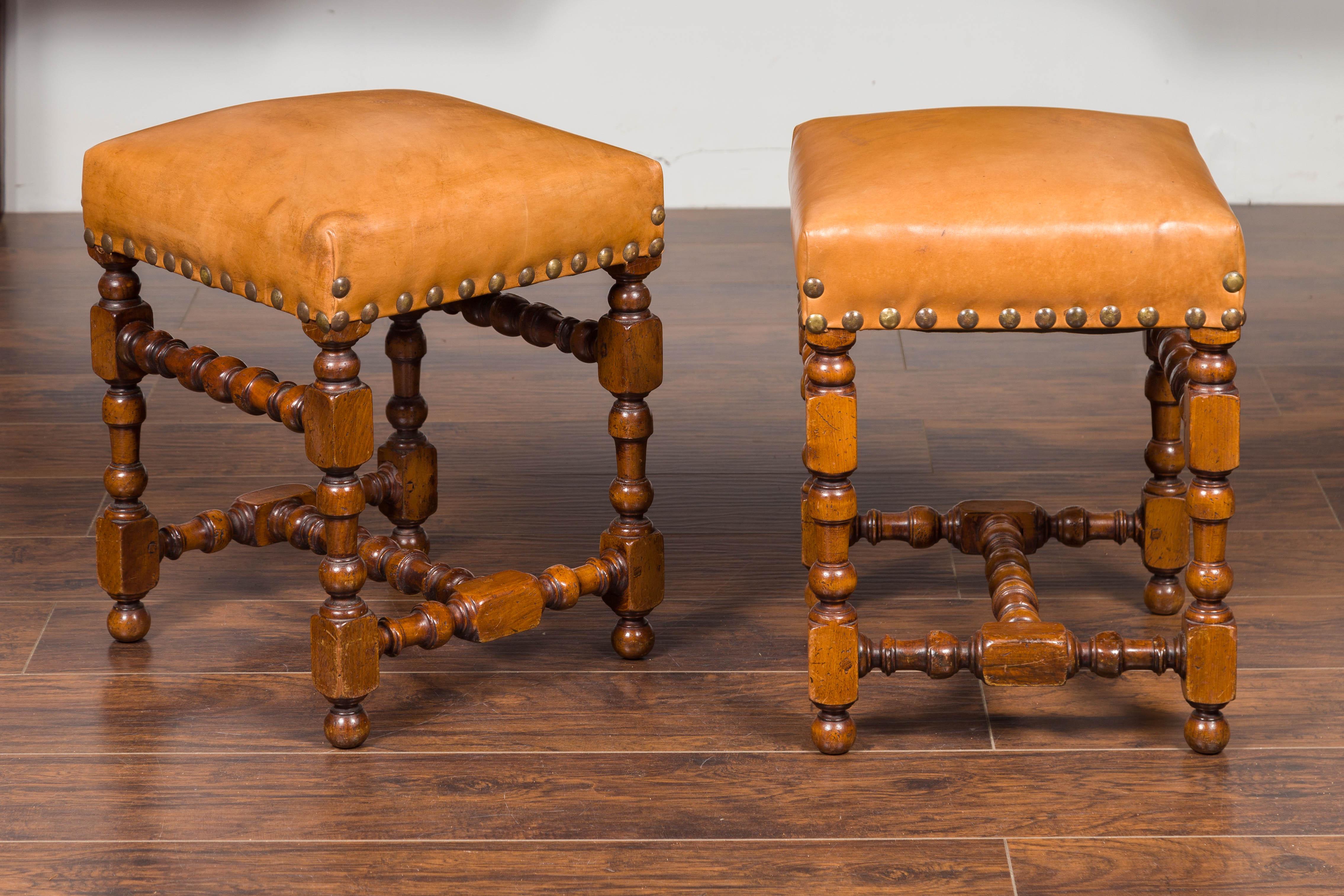 A pair of Italian walnut stools from the mid-19th century, with newer leather tops, turned legs and H-form cross stretcher. Born in Italy during the 1850s, each of this pair of walnut stools features a rectangular leather top (one of which carries