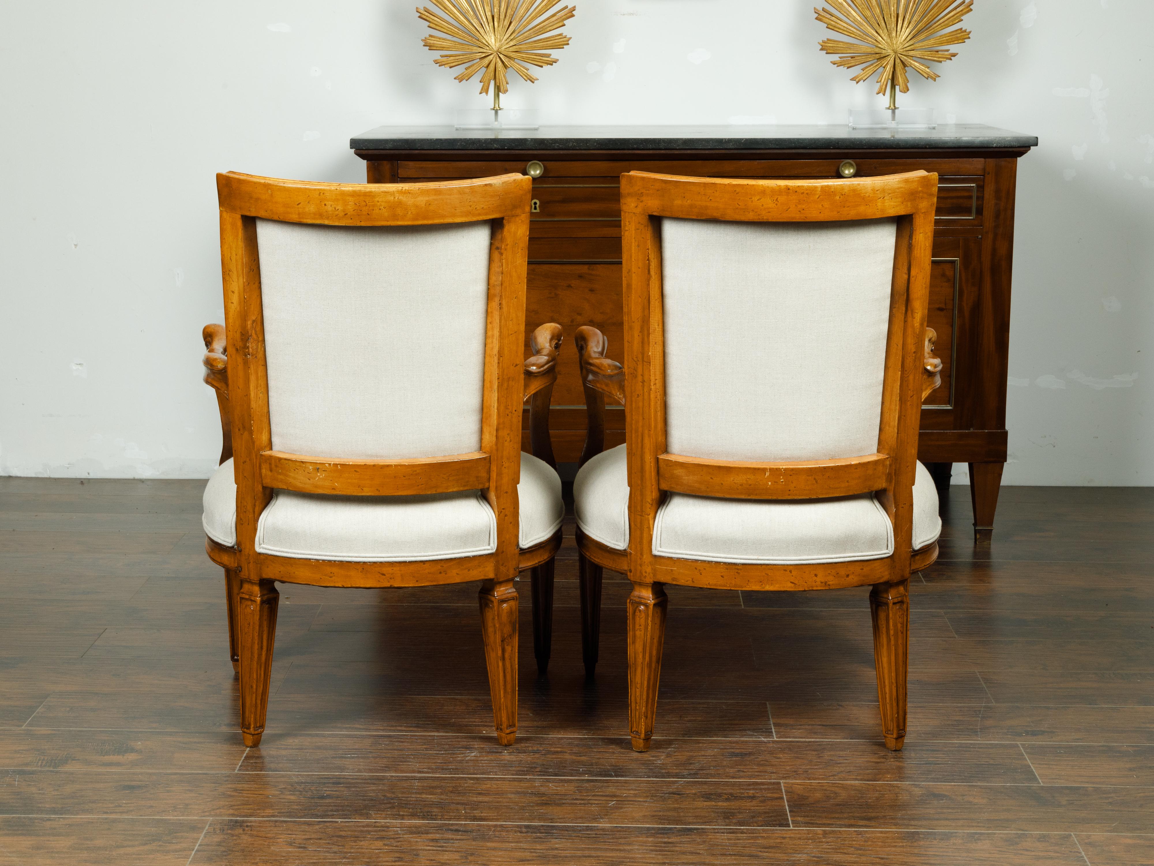 A pair of Italian walnut armchairs from the mid 19th century, with tapered legs and new upholstery. Created in Italy during the third quarter of the 19th century, each of this pair of walnut armchairs features a curving back connected to two sinuous