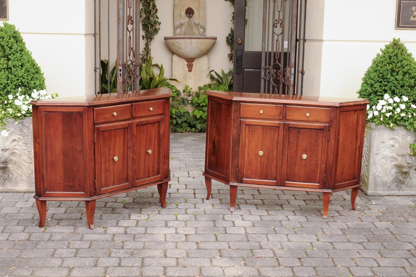 A pair of Italian walnut credenzas from the late 19th century, with canted sides and two drawers over double doors. Born in Italian during the third quarter of the 19th century, each of this pair of elegant walnut credenzas features a polygonal top