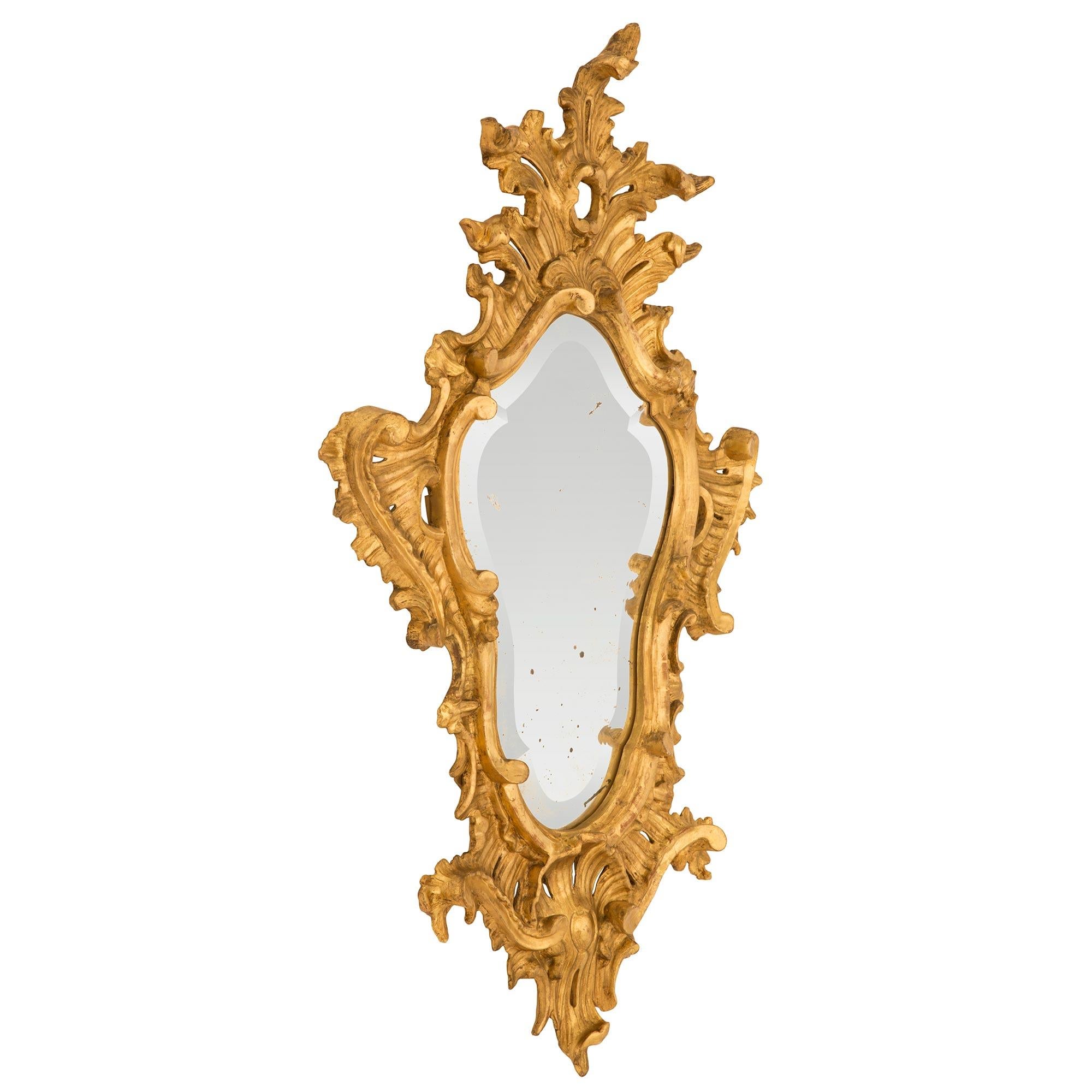 A striking pair of Italian 18th century Baroque period giltwood mirrors. Each mirror retains its original mirror plate with an exceptional and most decorative bevel following the charming scalloped shape of the frame. The frame displays stunning