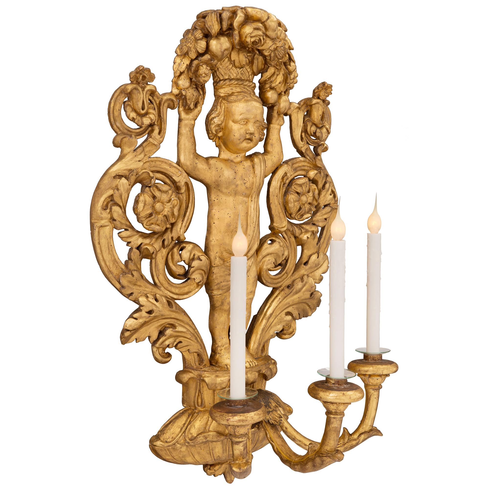 A stunning pair of Italian 18th century Baroque period giltwood three arm sconces, from Lucca. Each sconce is centered by a beautiful foliate bottom support from where the elegant arms branch out. Each arm is adorned with acanthus leaves and