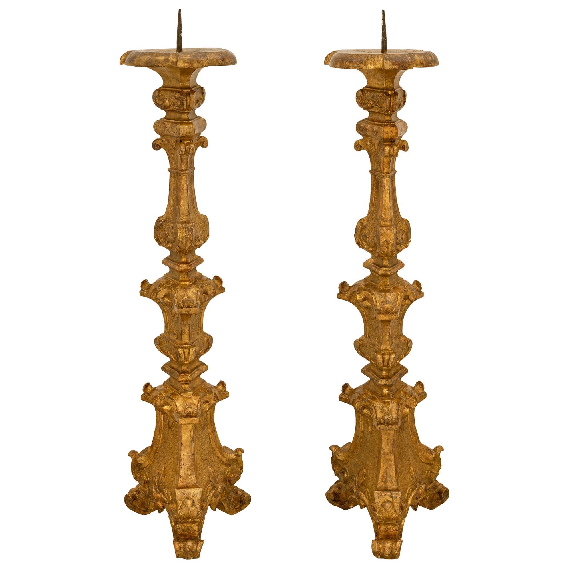A striking pair of Italian 18th century Baroque period Mecca Torchières. Each Torchière is raised by three elegant scrolled feet below the triangular shaped lightly curved base with lovely foliate carvings and a fine hammered design. The central