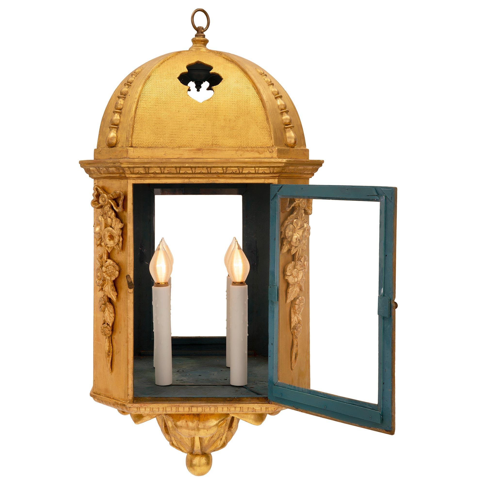 A striking and most decorative pair of Italian 18th century Baroque st. giltwood lanterns. Each octagonal lantern is centered by a beautiful bottom foliate finial with a fine ball. Above the mottled foliate bands are hand blown fitted glass panes