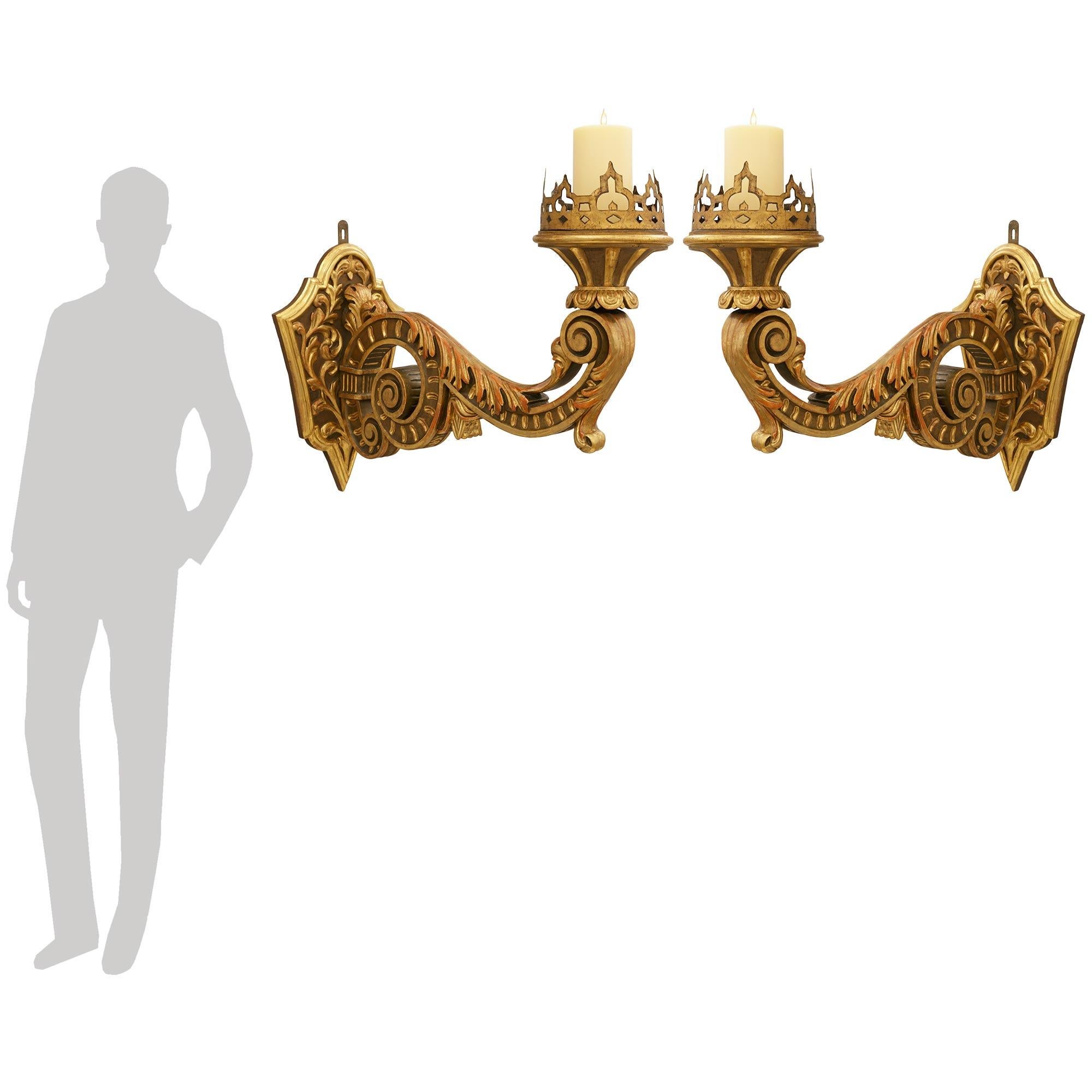 Una splendida coppia di appliques barocche del XVIII secolo in legno patinato e legno dorato. Ogni applique Bras de Lumière, ricca di dettagli, è sostenuta da una splendida piastra posteriore marrone patinata a forma di scudo con disegni a volute in