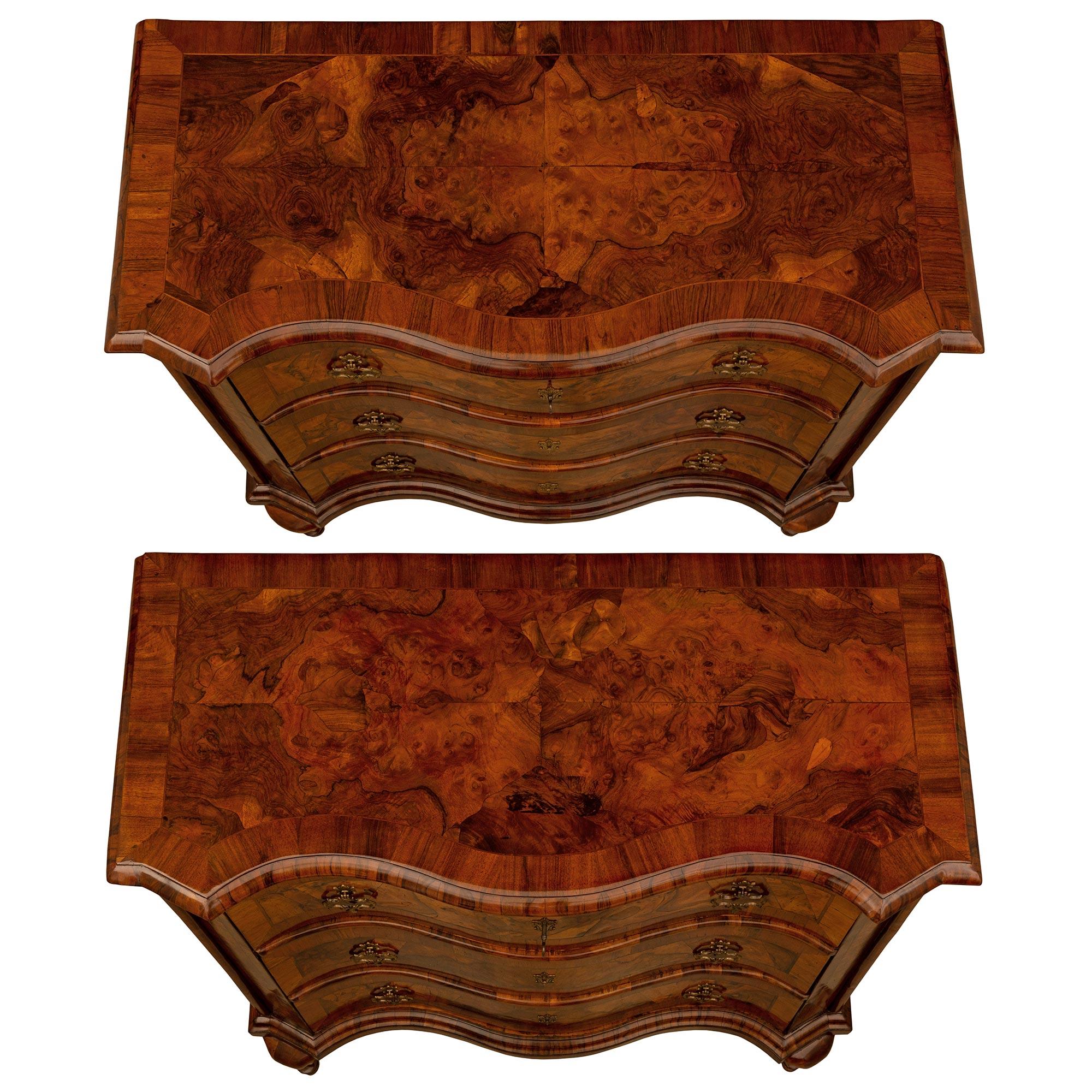 A stunning and extremely decorative pair of Italian 18th century Baroque st. Walnut, burl Walnut, and bronze commodes. Each three drawer chest is raised by unique and most elegant scrolled tapered legs with fine mottled feet. The bombee serpentine