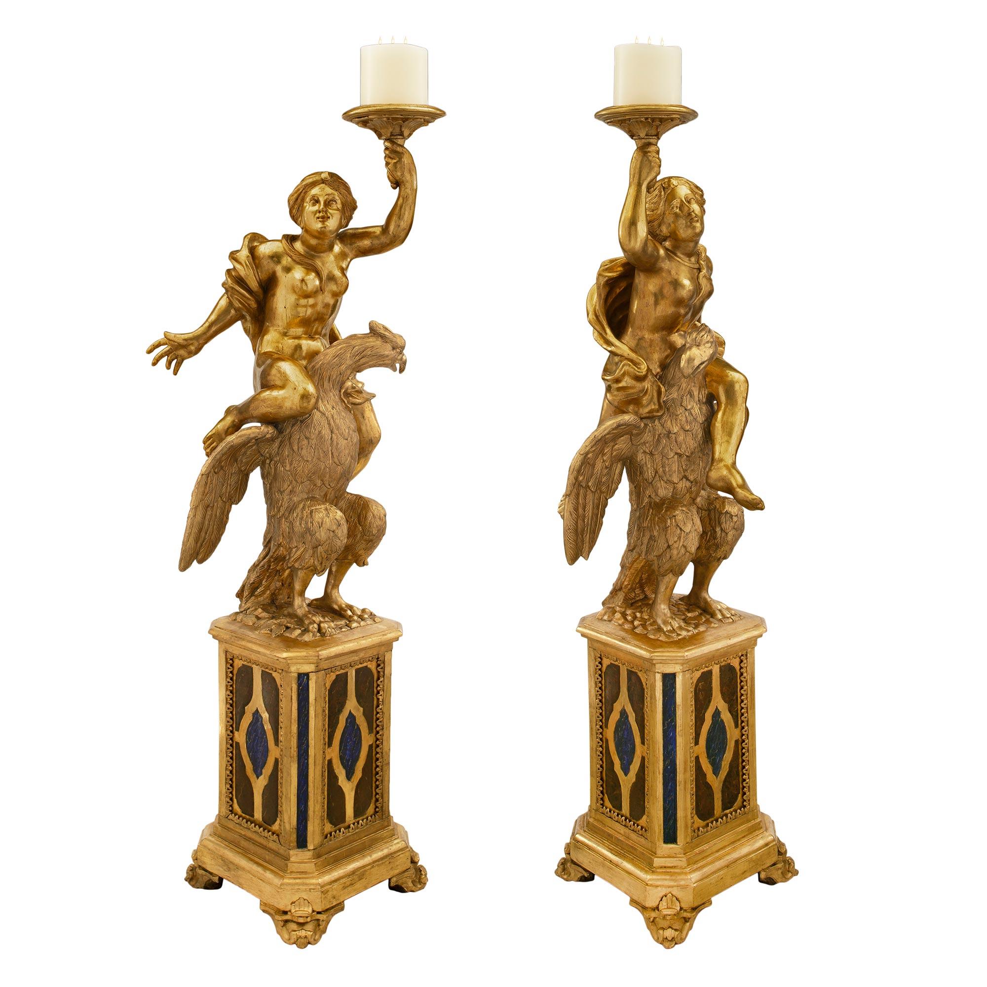 A stunning and large scale true pair of Italian 18th century giltwood and faux painted Baroque Torchières. Each Torchière is raised by a striking pedestal with fine scrolled foliate feet and and octagonal stepped base. Each side displays impressive