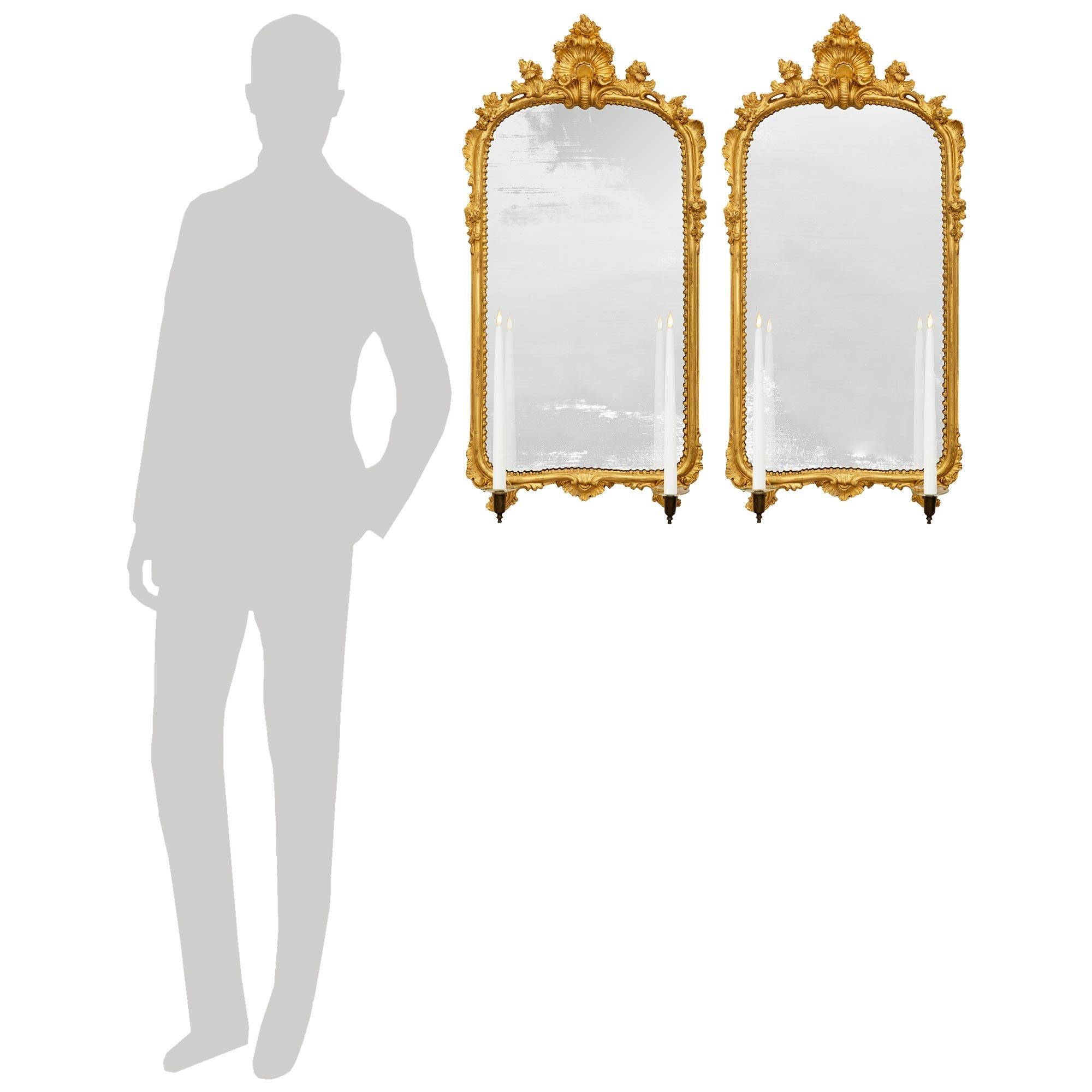 A wonderful and most decorative pair of Italian 18th century Louis XV st. Giltwood and patinated Bronze mirrored sconces. This stunning pair of sconces displays two bottom patinated Bronze candle cups held within a scalloped shaped Giltwood scroll.
