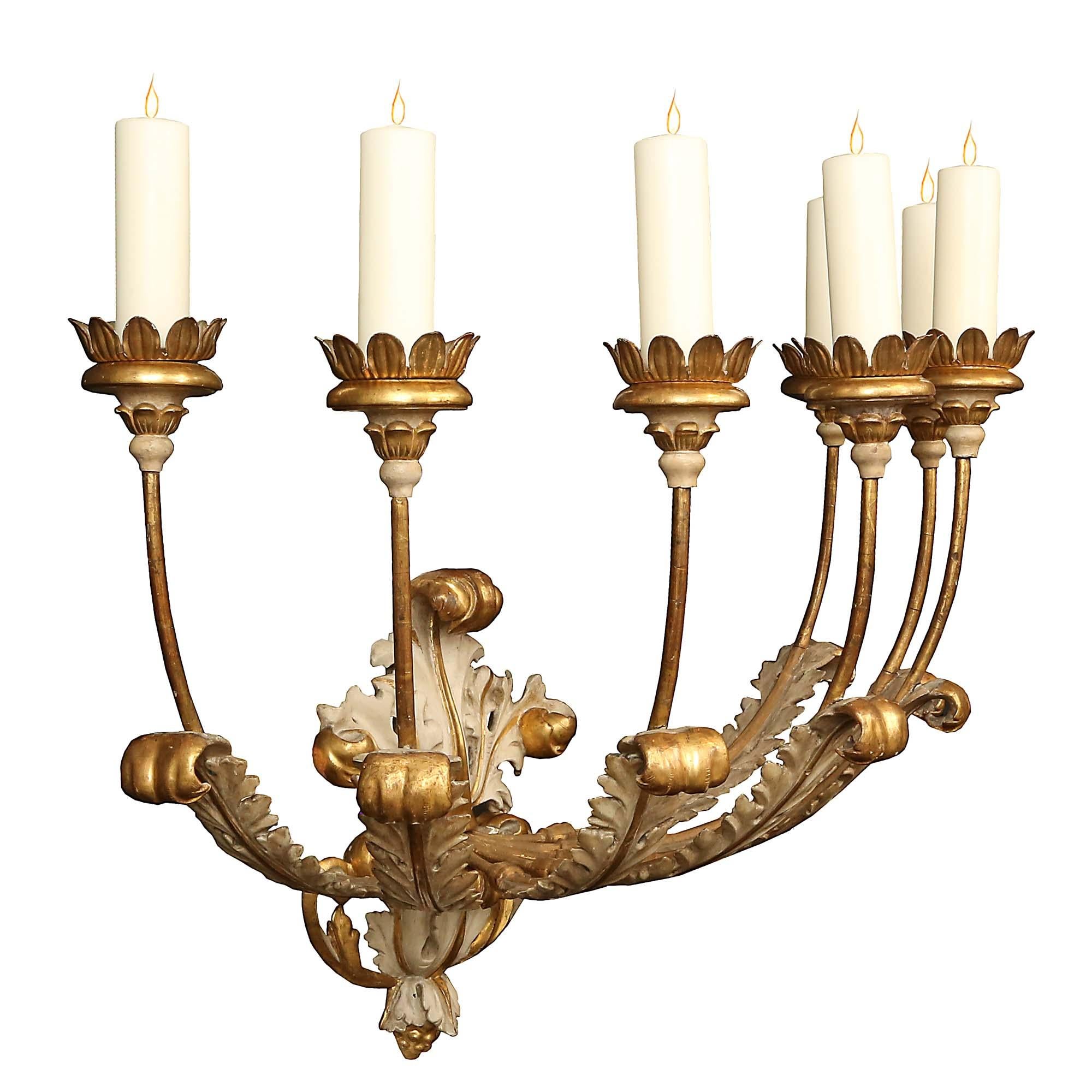 A magnificent and monumental pair of Italian 18th century giltwood and patinated seven arm sconces. The stunning sconces are centered by a striking and superbly carved bottom acorn finial with rich scrolling acanthus leaves in a gilt and patinated