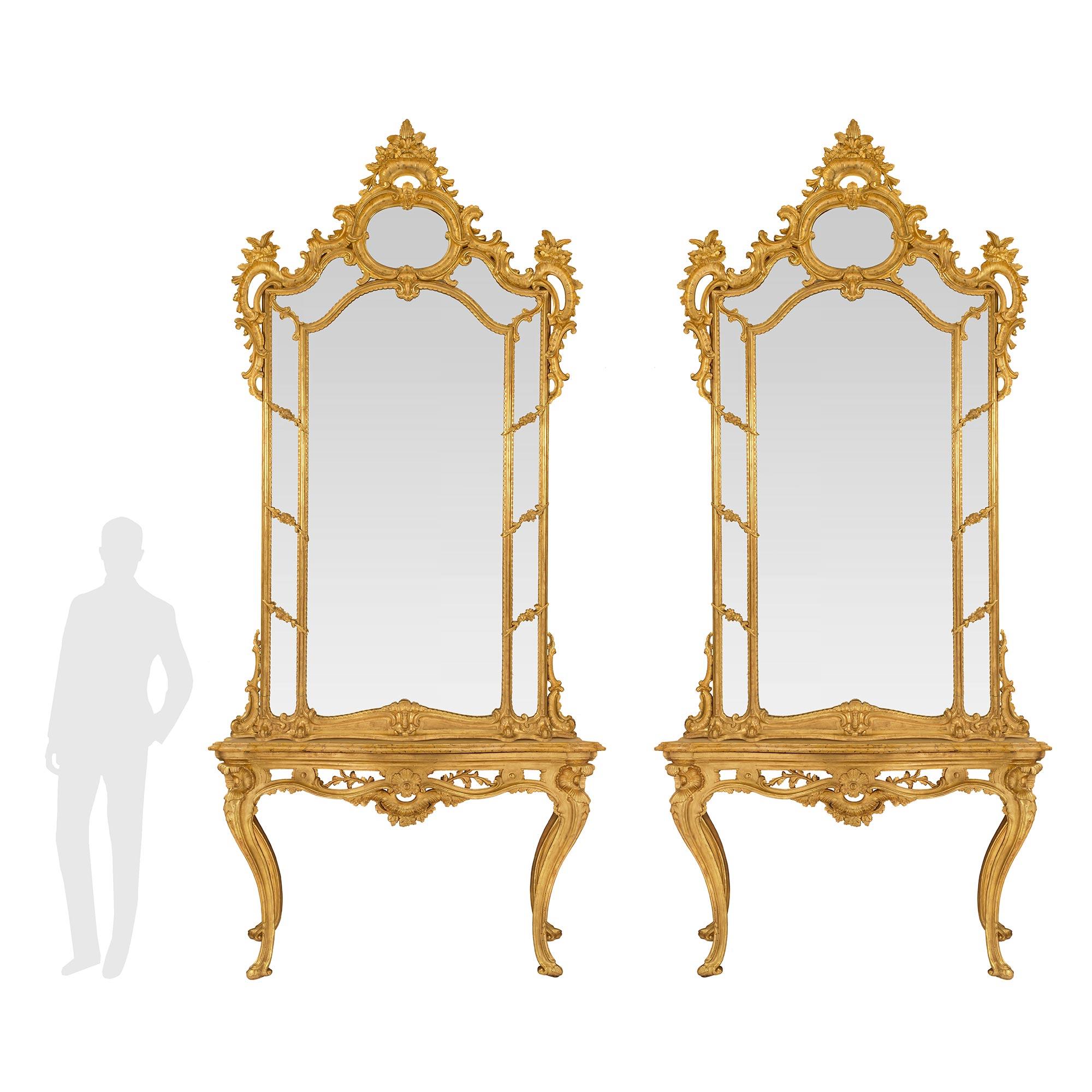 A sensational and palatially scaled pair of Italian 18th century Louis XV period giltwood and marble Neapolitan consoles with their original matching mirrors. Each stunning console is raised by most elegant tapered cabriole legs with most decorative
