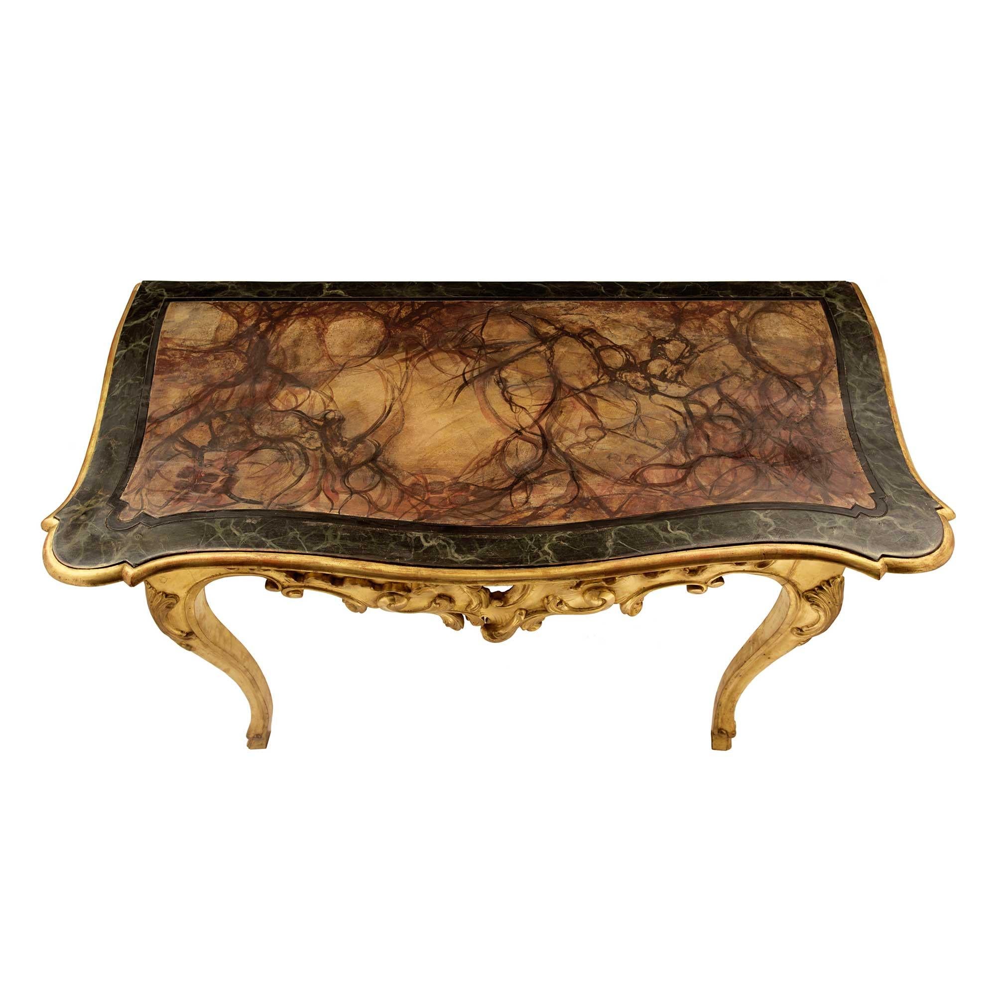 A striking pair of Italian 18th century Louis XV period giltwood and faux painted marble free standing Genovese consoles. Each beautiful console is raised by elegant cabriole legs with hoof feet and lovely foliate carved corner reserves. The lovely