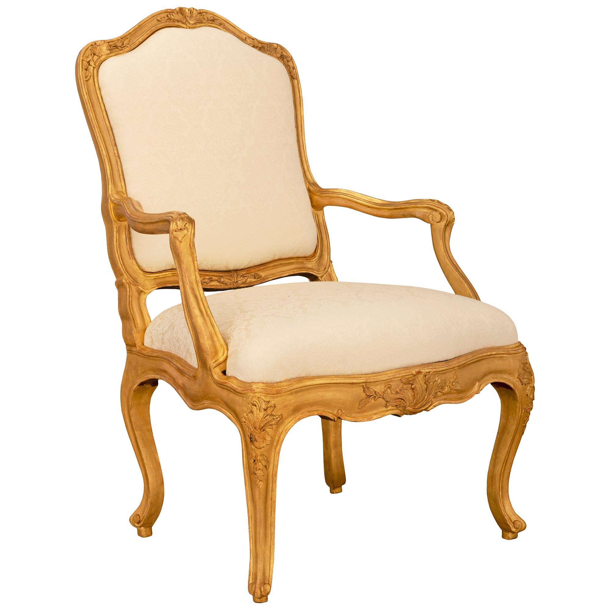 An elegant pair of Italian 18th century Louis XV period giltwood armchairs. Each armchair is raised by slender cabriole legs with fine scrolled feet and beautiful foliate corner designs. A delicate fillet extends up each leg and along the scalloped