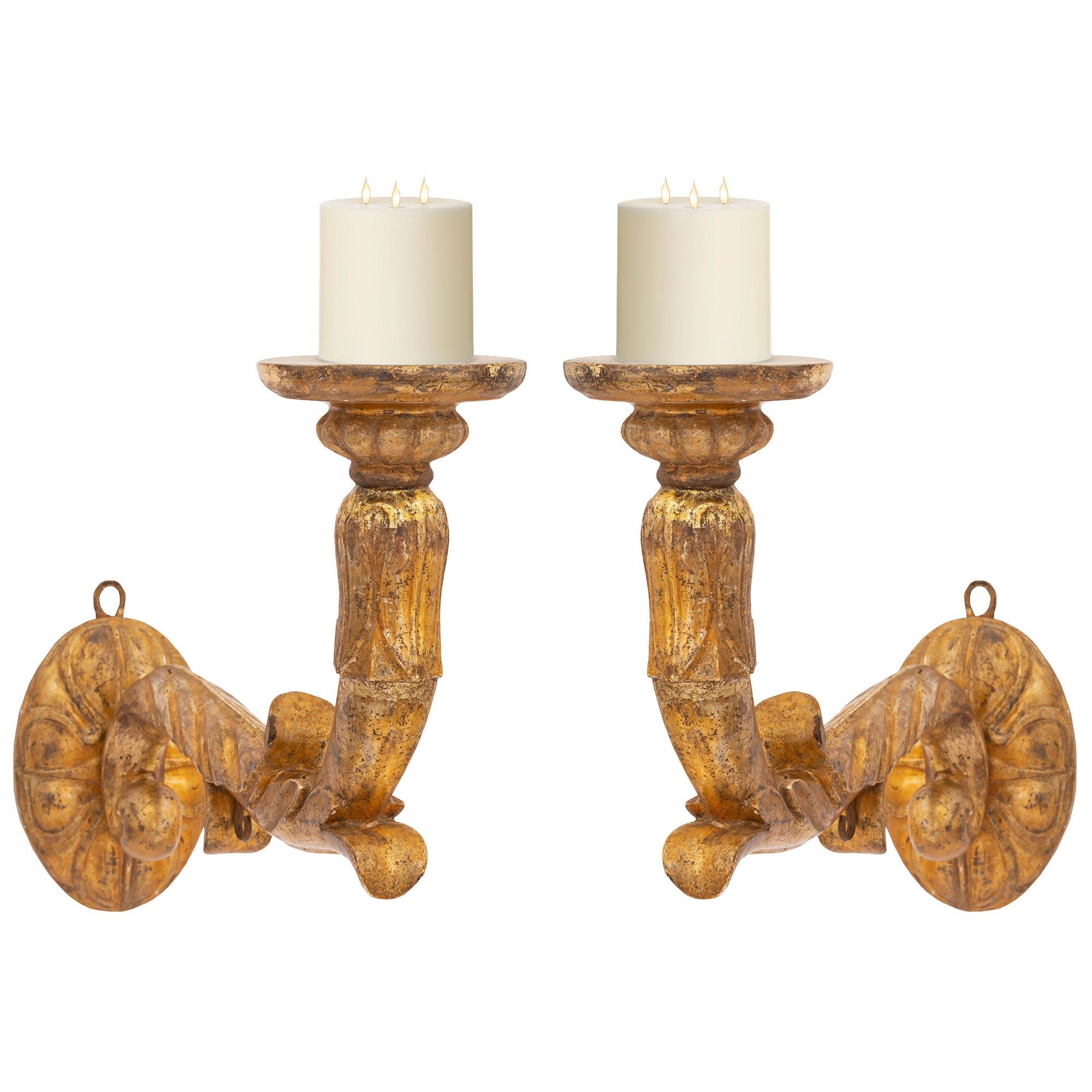 A handsome and most impressive pair of Italian 18th century Mecca Bras de Lumière sconces. Each one arm sconce is centered by an oval backplate with an elegant carved reeded floral design from where the arms branch out. Each scrolled arm is adorned