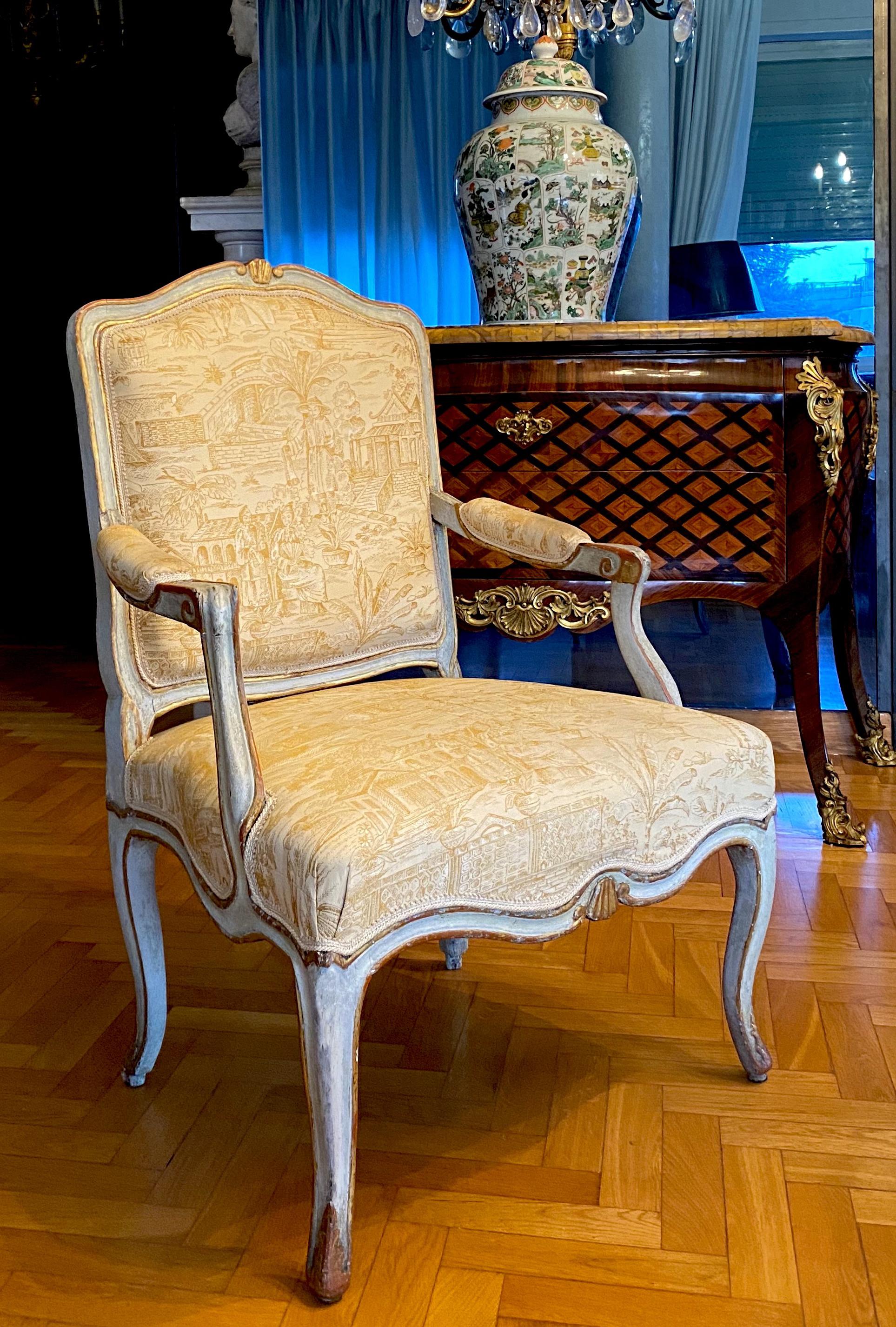 A pair of Italian, 18th century parcel-gilt and pale-grey painted armchairs with a shaped back decorated with shell-carved crest, scrolling armrests on a serpentine seat on cabriole legs,
Covered with cream Chinoise upholstery.