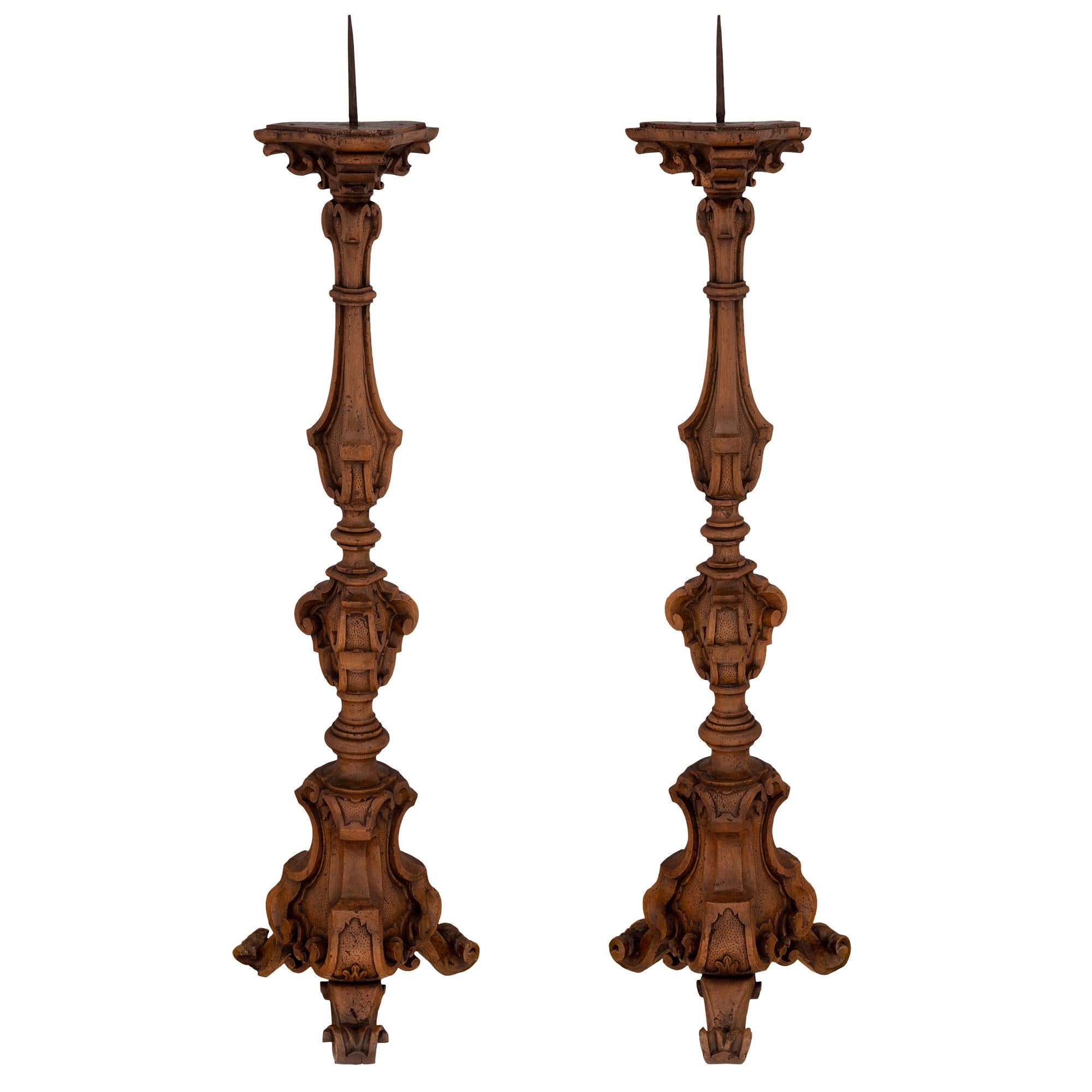 An impressive and most decorative pair of Italian 18th century Regence st. solid walnut Torchières. Each Torchière is raised by three scrolled feet below the beautiful and uniquely shaped carved supports with fine hammered designs. The central