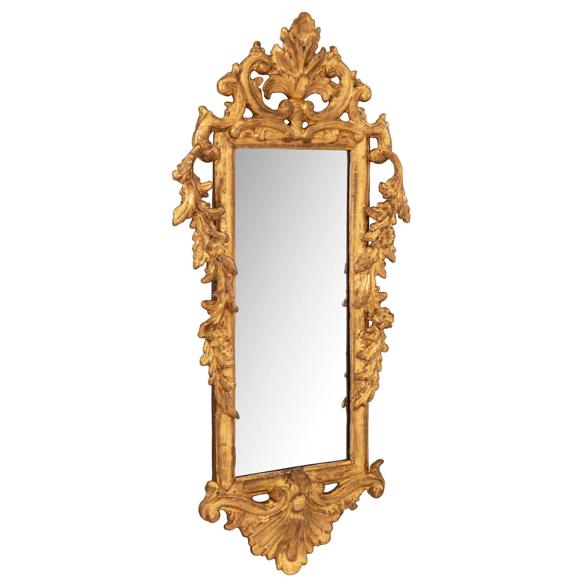 Une très belle paire de miroirs italiens en bois doré de style Rococo du 18ème siècle. Chaque miroir d'une taille unique est placé dans un cadre rectangulaire en bois doré avec des guirlandes florales drapées en forme de 