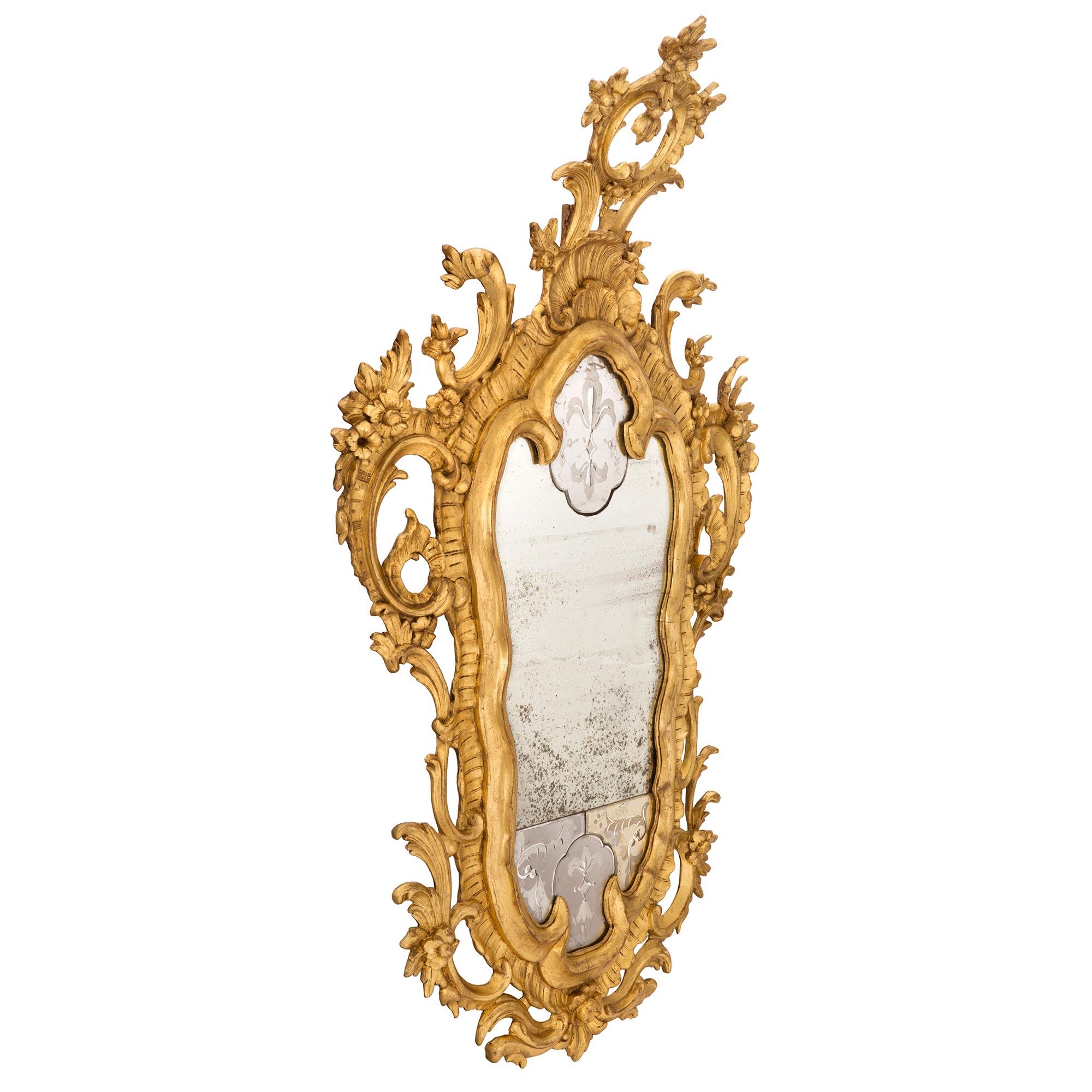 A stunning pair of Italian 18th century Venetian style giltwood mirrors. Each most decorative mirror retains all of their original mirror plates with the top and bottom plates displaying beautiful wonderfully executed etched foliate designs and