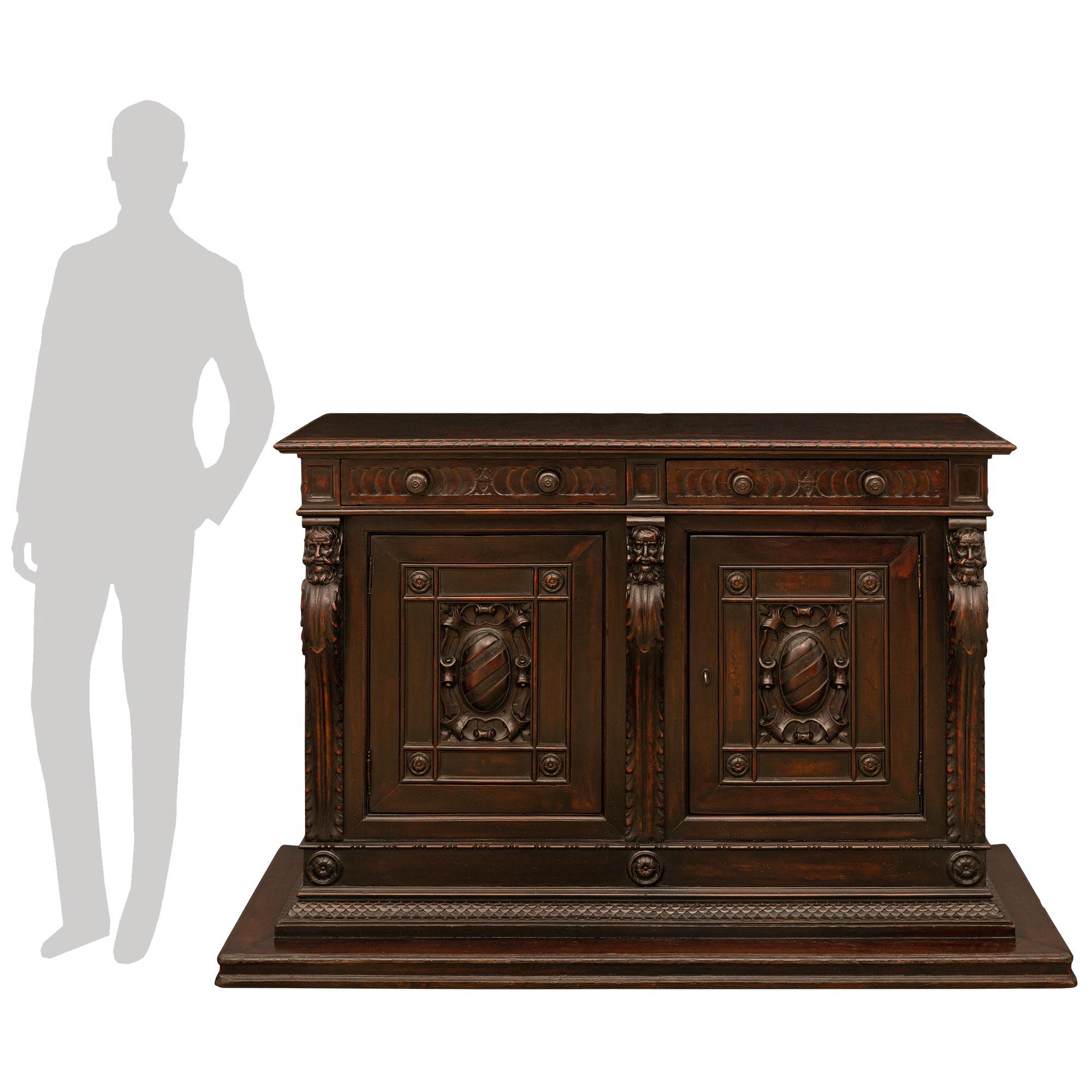 A most handsome and impressive pair of Italian 18th century, two door, two drawer walnut buffets, from Northern Italy. Each buffet is raised by a unique and most decorative mottled rectangular base below a beautiful carved foliate band. At the