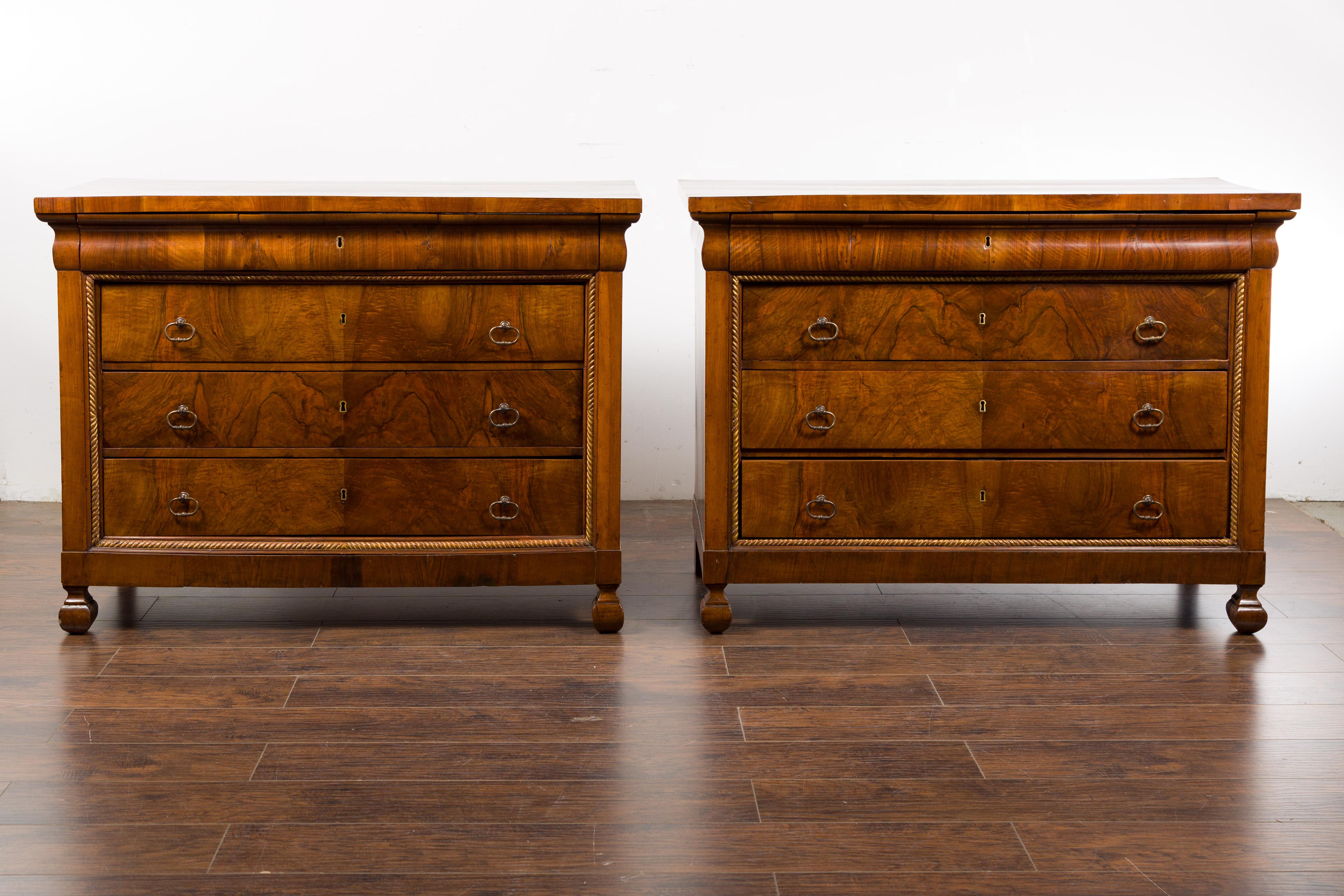 A pair of Italian 18th century walnut commodes with bookmatched veneer, four drawers and petite carved feet. Immerse yourself in the historical grandeur of this pair of Italian 18th-century walnut commodes. These captivating pieces present the