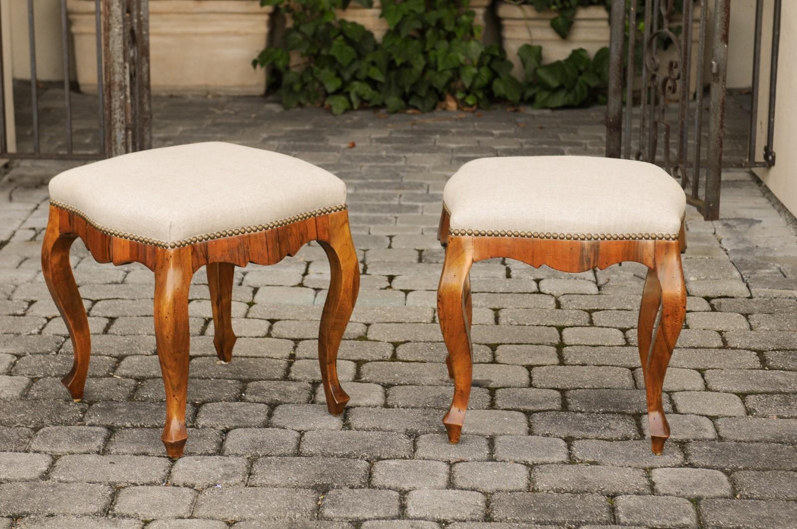 A pair of Italian Rococo style olivewood stools from the early 20th century, with reupholstered seats. Born in Italy during the early years of the 20th century, each of this pair of stools features a square seat, newly upholstered with a linen