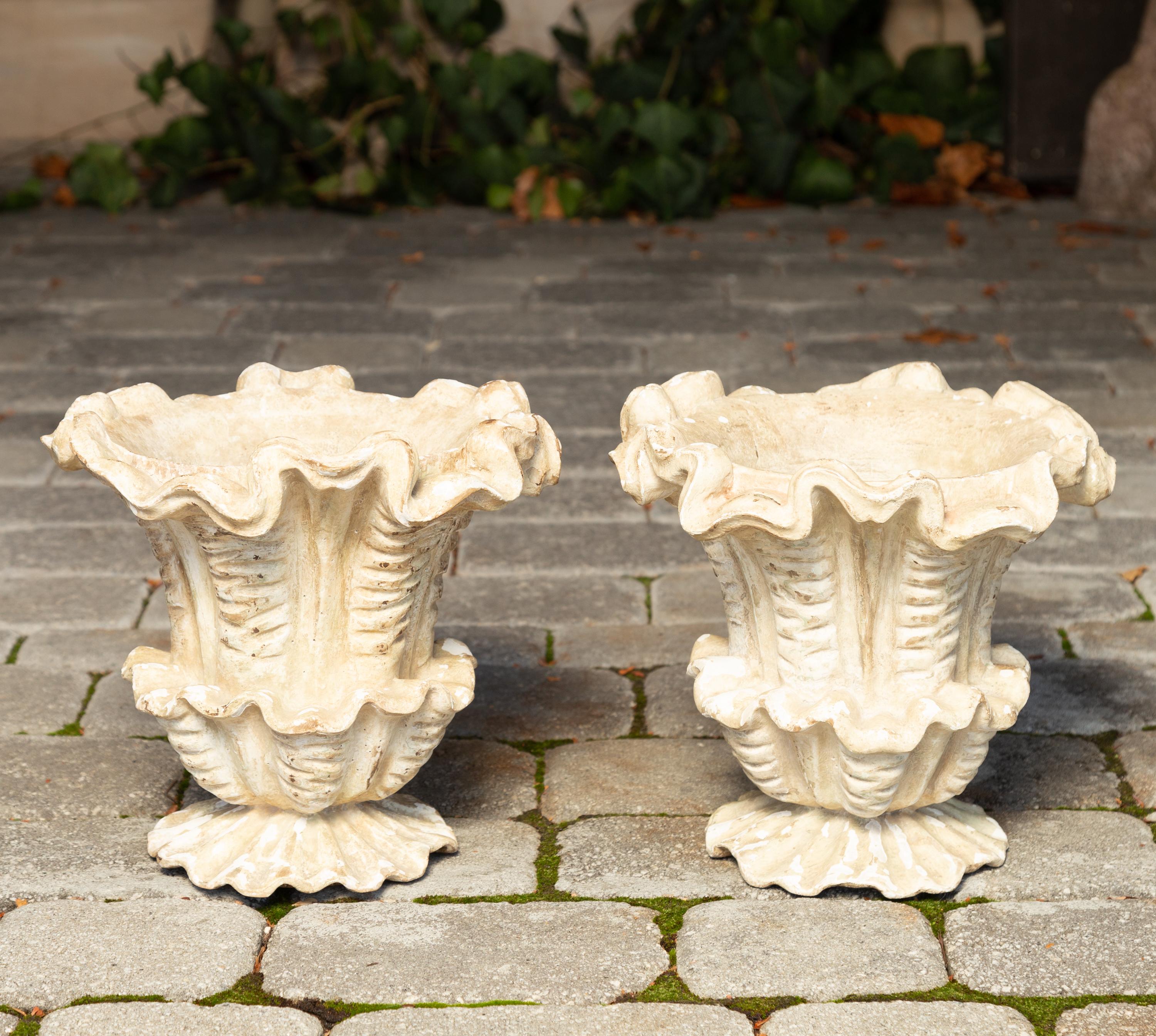 A pair of Italian carved and painted wooden floral-shaped urns from the first half of the 20th century with weathered finish. Born in Italy during the second quarter of the 20th century, each of this charming pair of carved urns attracts our