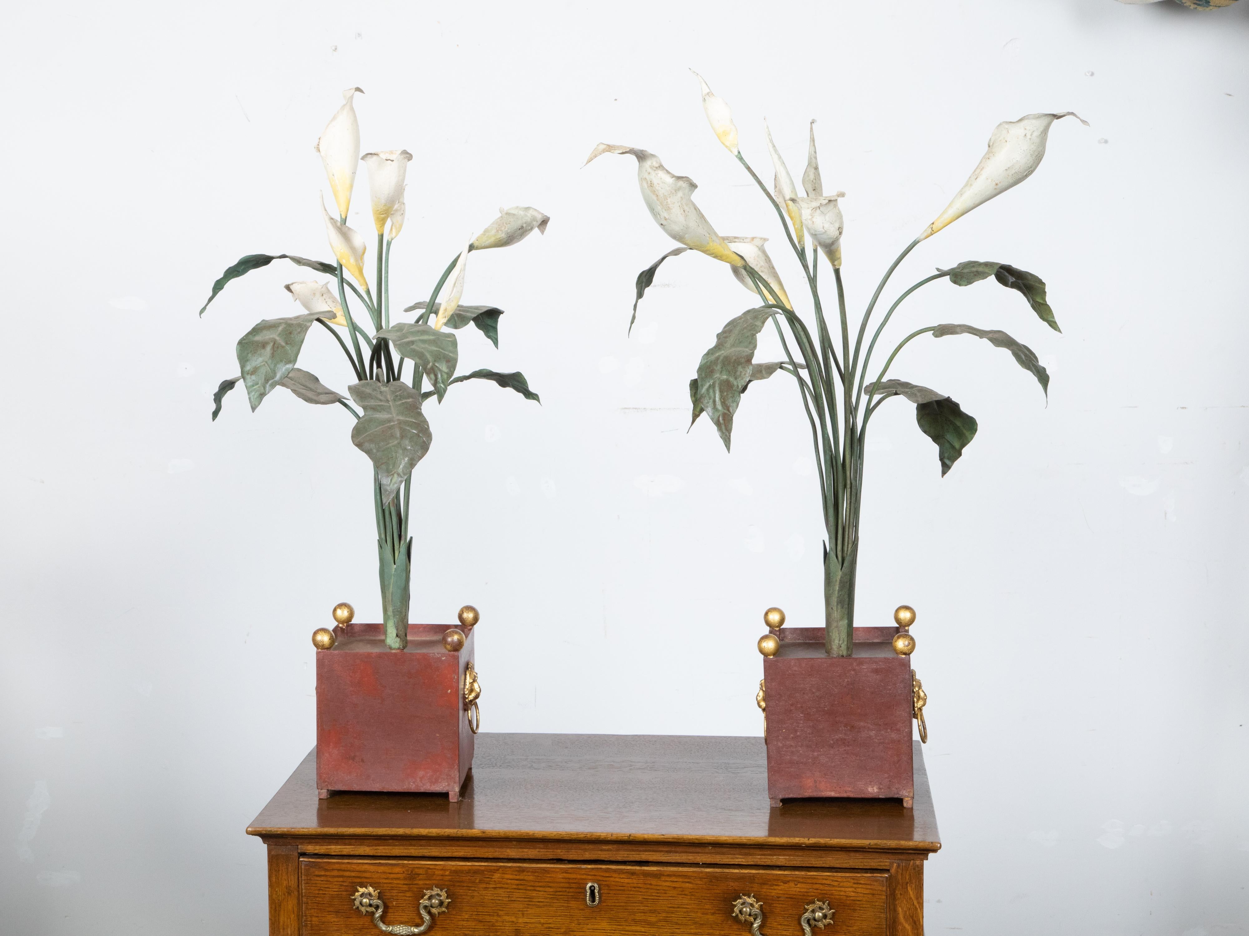 A pair of Italian vintage painted tôle Calla Lilies sculptures from the early 20th century, with white, yellow and green tones, in red containers. Created in Italy during the second quarter of the 20th century, each of this pair of sculptures is