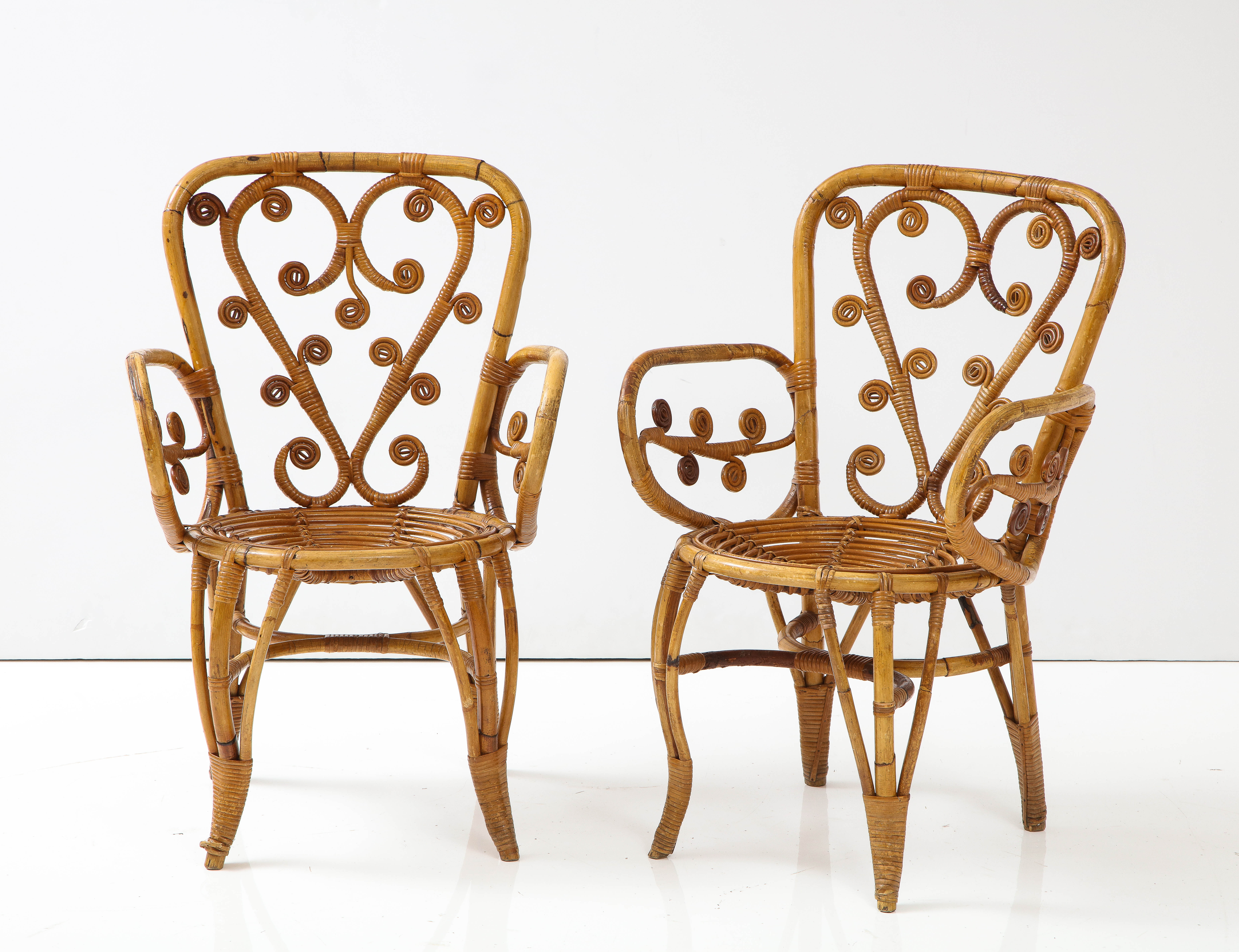 A pair of charming and whimsical Italian 1950's bamboo armchairs; the back with heart shape and scroll motif, the arms beautifully curved with branch like fanciful scroll decorations; the whole exquisitely and intricately carved and supported on