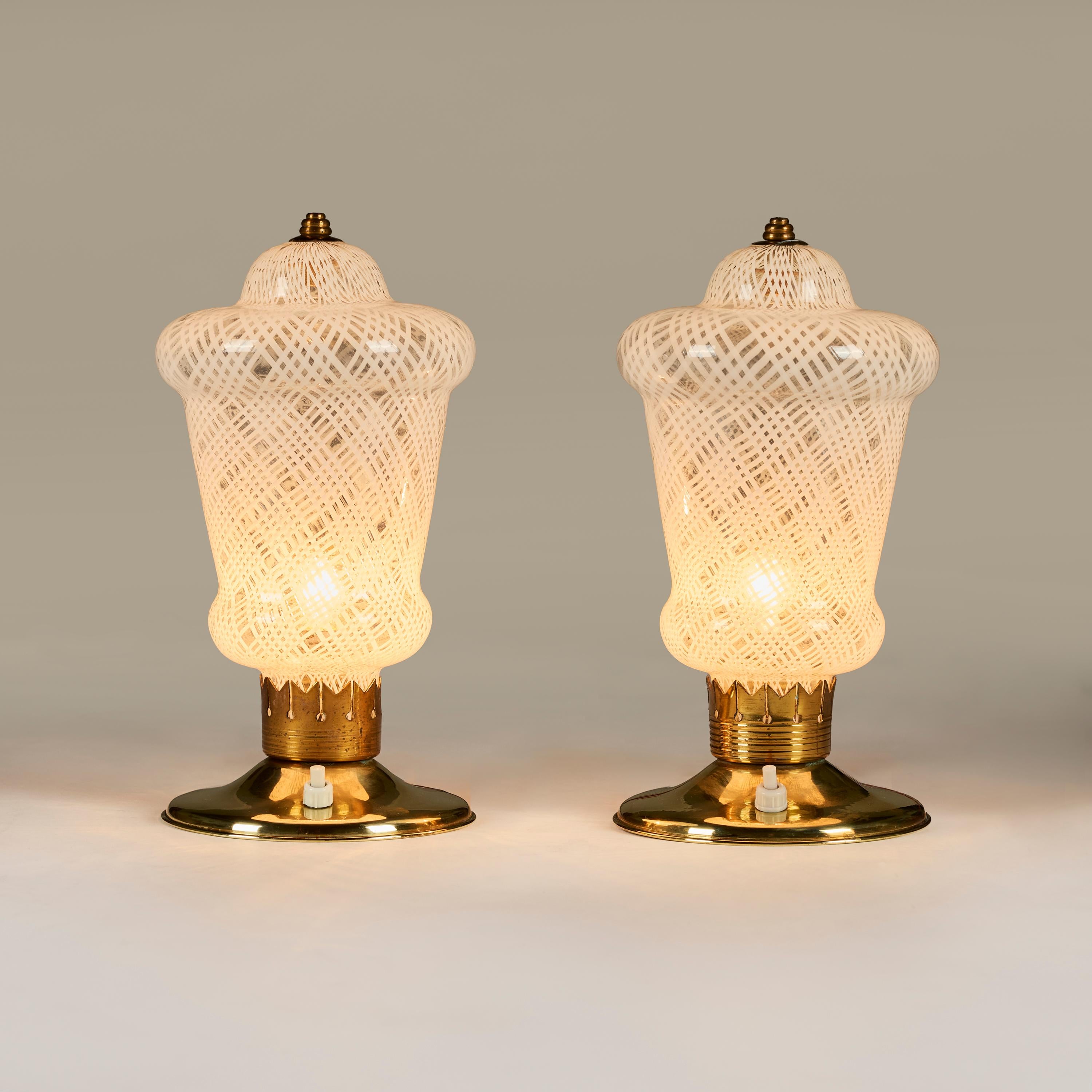 Well proportioned pair of Italian 1950s Murano table lamps with decorative and unusual Reticello lattice patterning to the glass. Brass filial top, brass circular base with on/off button switch and decorative brass stem detailing. Exudes a lovely