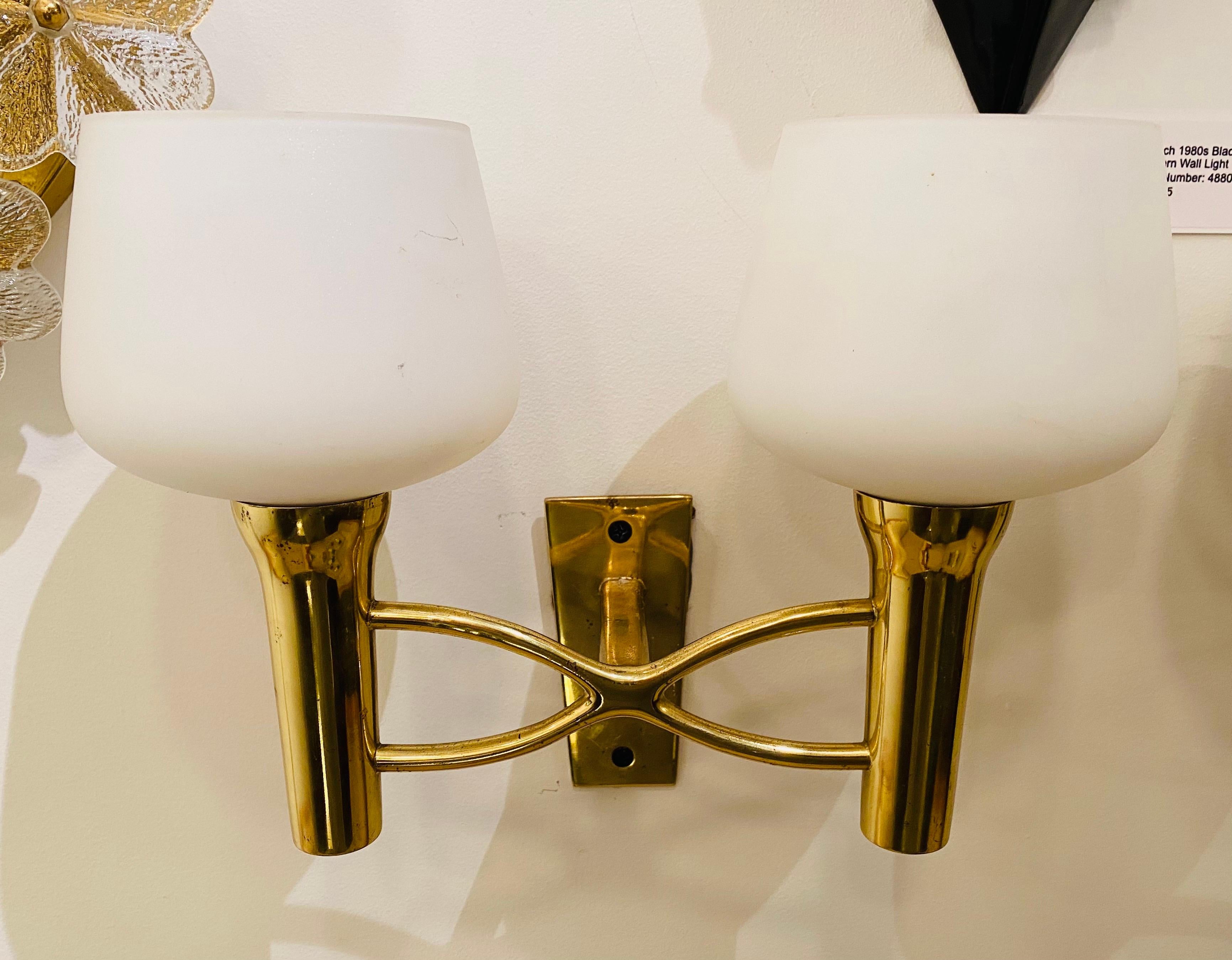 An original pair of 1950s Italian sconces with decorative aged polished brass “X” fixtures with double sockets holding white glass shades. Newly rewired.