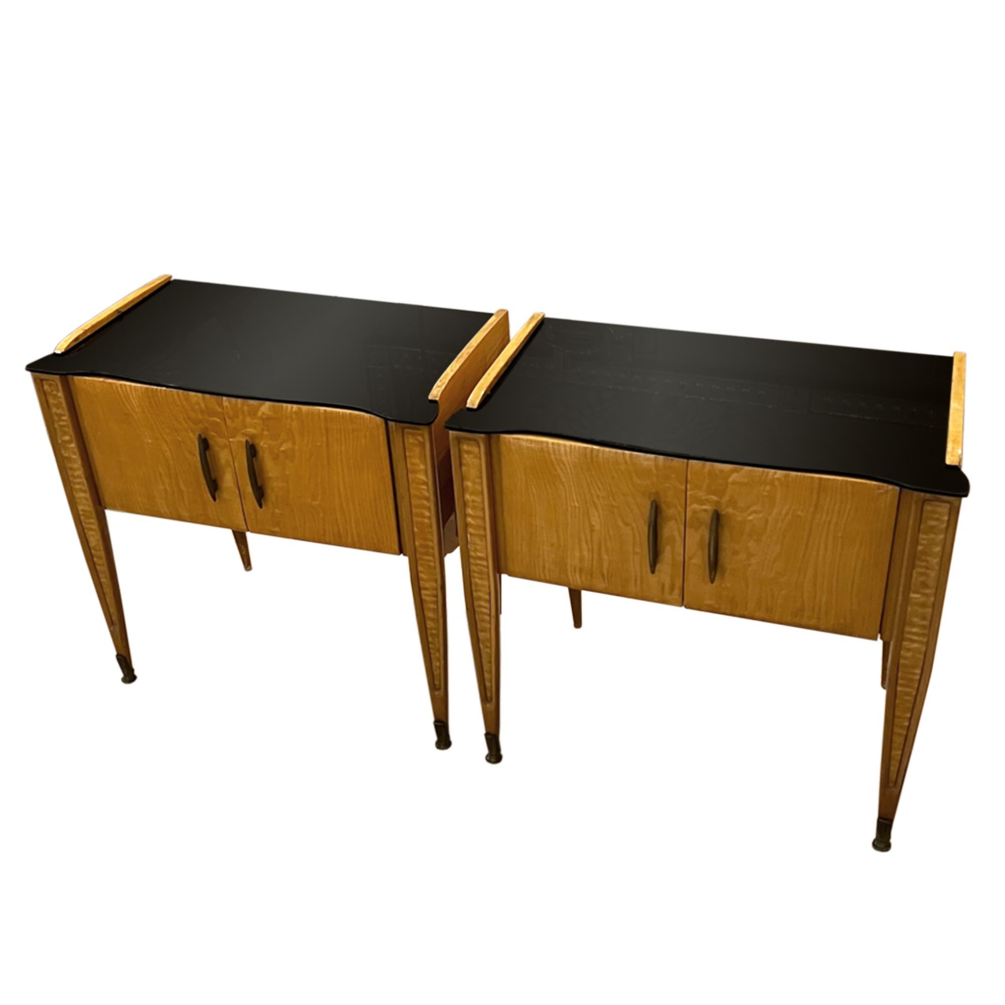 A lovely pair of bedside tables - neat, elegant design with good storage. 

These nightstands have stylish black glass tops and tapered legs finishing in metal feet at the front. 

Made from birch wood in Italy in the 1950s.