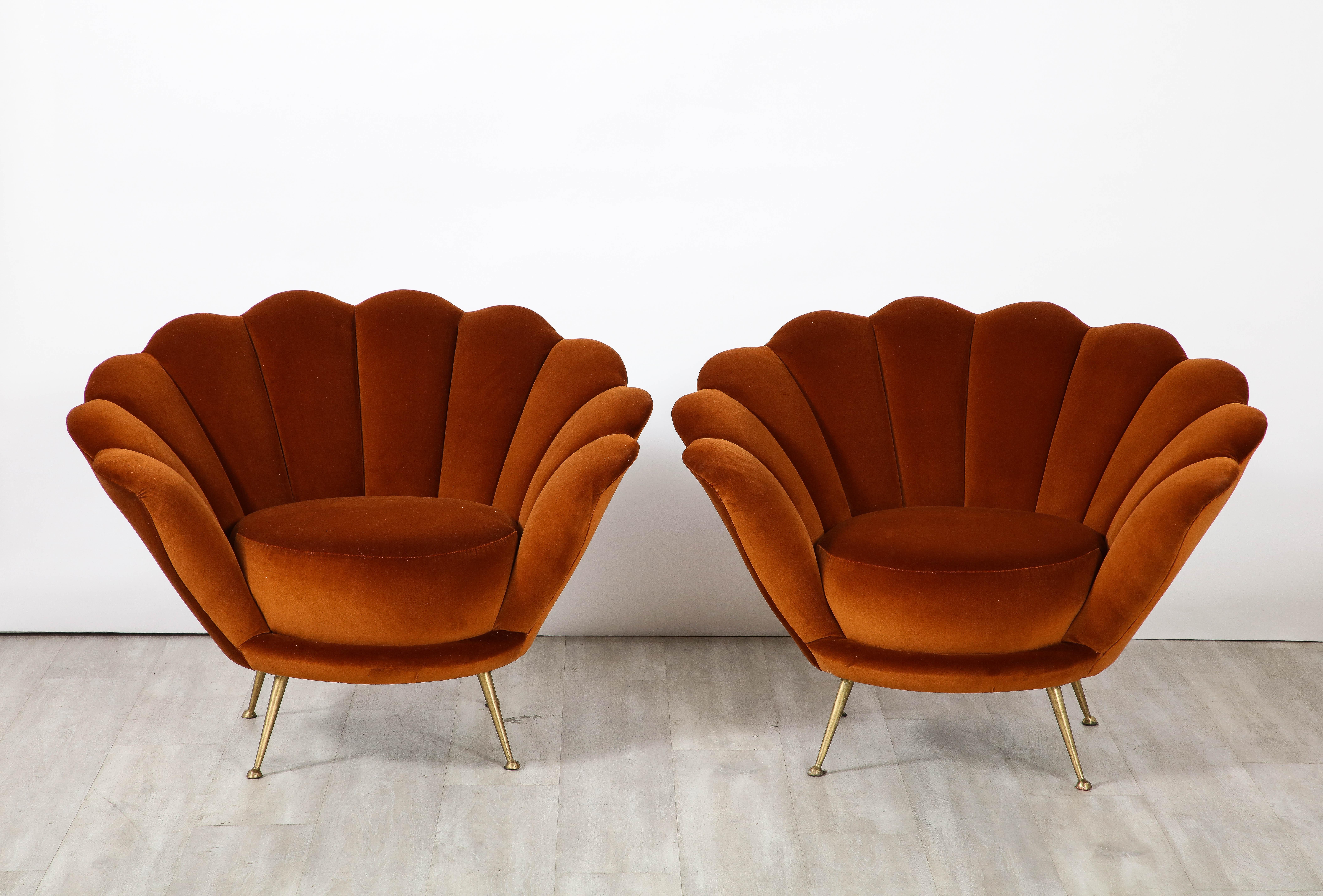 A decadently designed pair of Italian 1950's lounge chairs with a scalloped or petal shaped form. These classic and exquisite lounge chairs have been fully restored and newly reupholstered in a luxurious and rich cotton apricot colored velvet. The