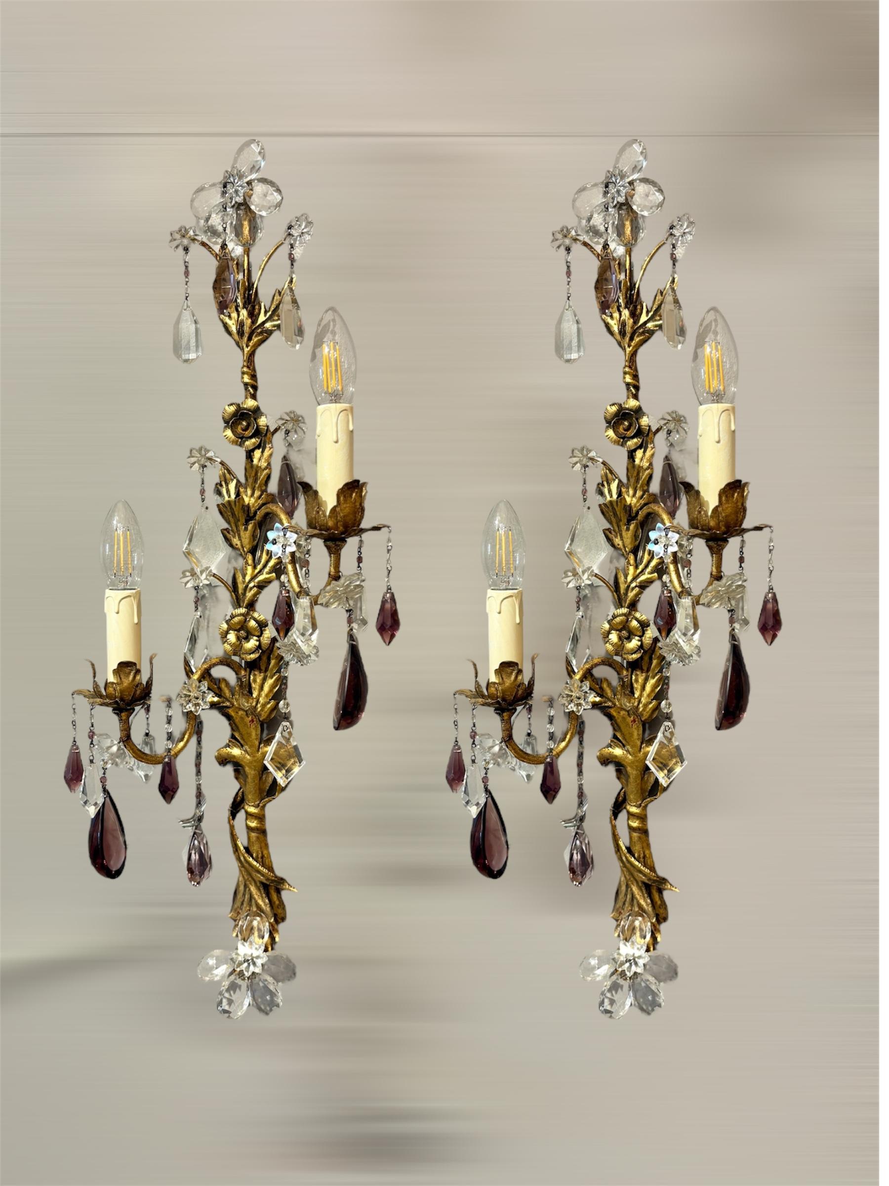 Questa elegante coppia di applique italiane, risalenti agli anni '50, è realizzata in ottone dorato con raffinati ornamenti in cristallo di Boemia, progettati nel caratteristico stile Florentine. Ogni applique presenta tre bracci luminosi a forma di