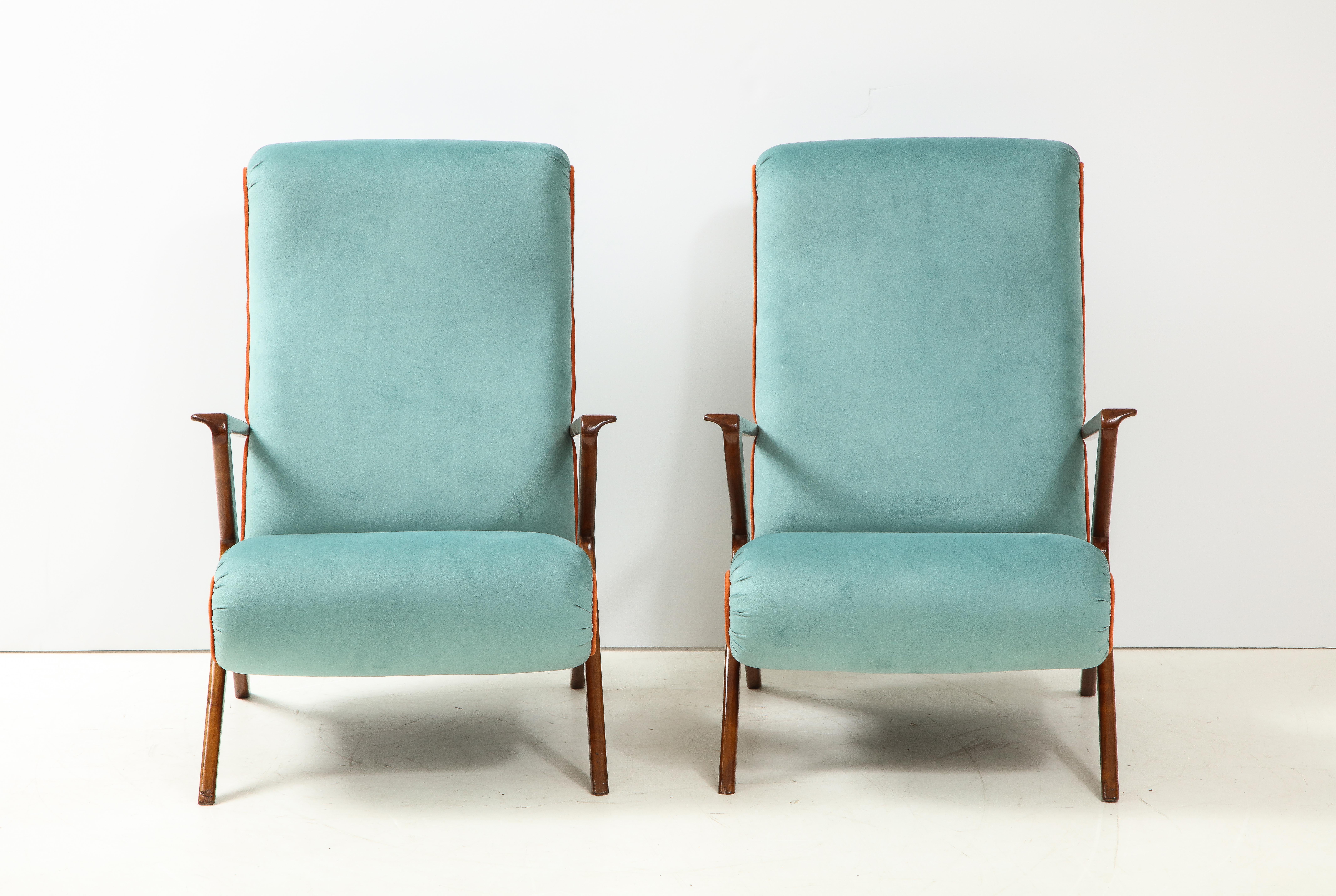 A pair of Italian 1950s sculptural walnut armchairs or lounge chairs. The chairs have fantastic sculptural angles, solid walnut frames, with brass details and are newly upholstered in an Italian soft blue ultra-suede with an apricot/orange piping.