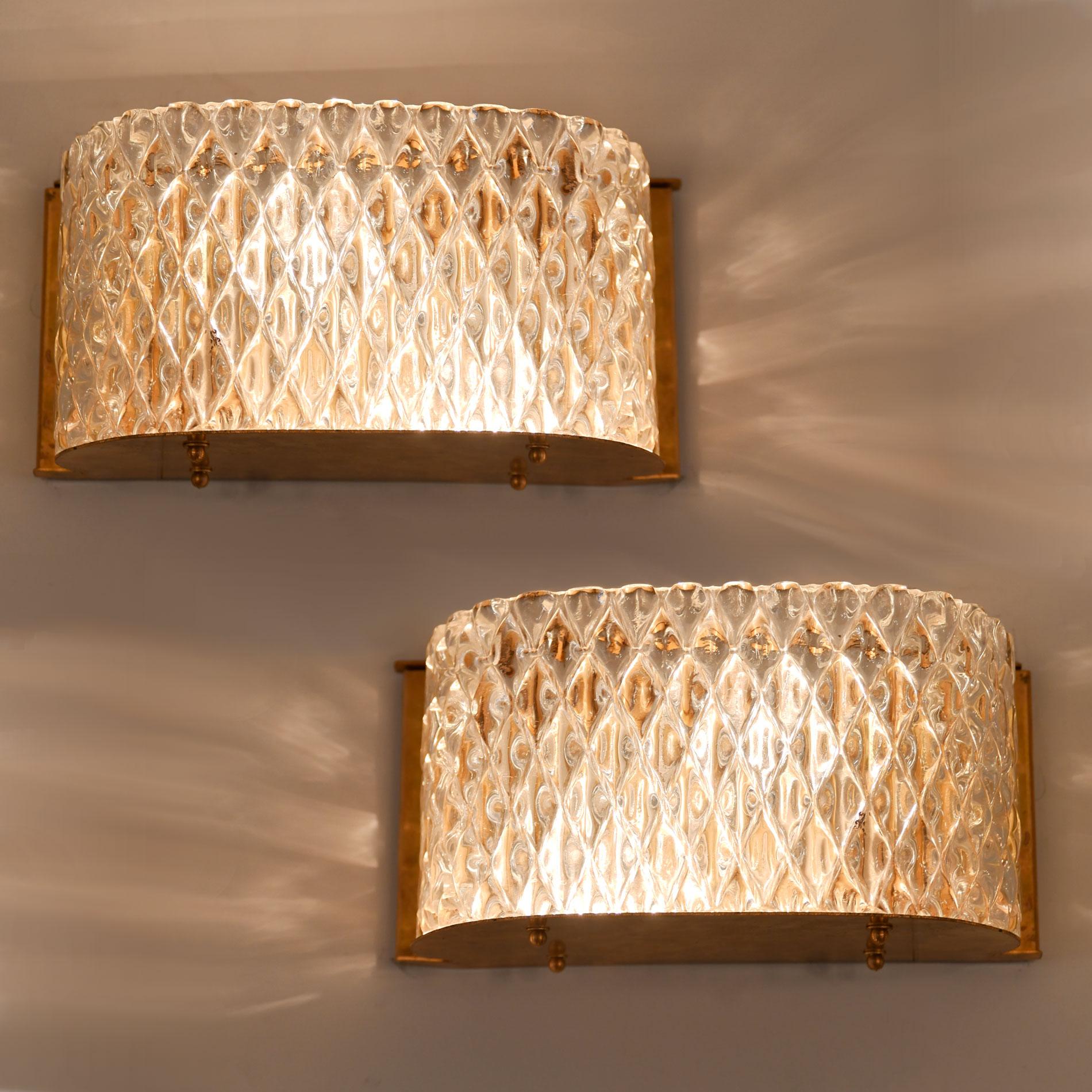 Glamorous criss-cross textured glass wall light with curved corners. The overall effect of the glass alongside the reflection of the brass back plate and base creates a lovely diffused warm light.
