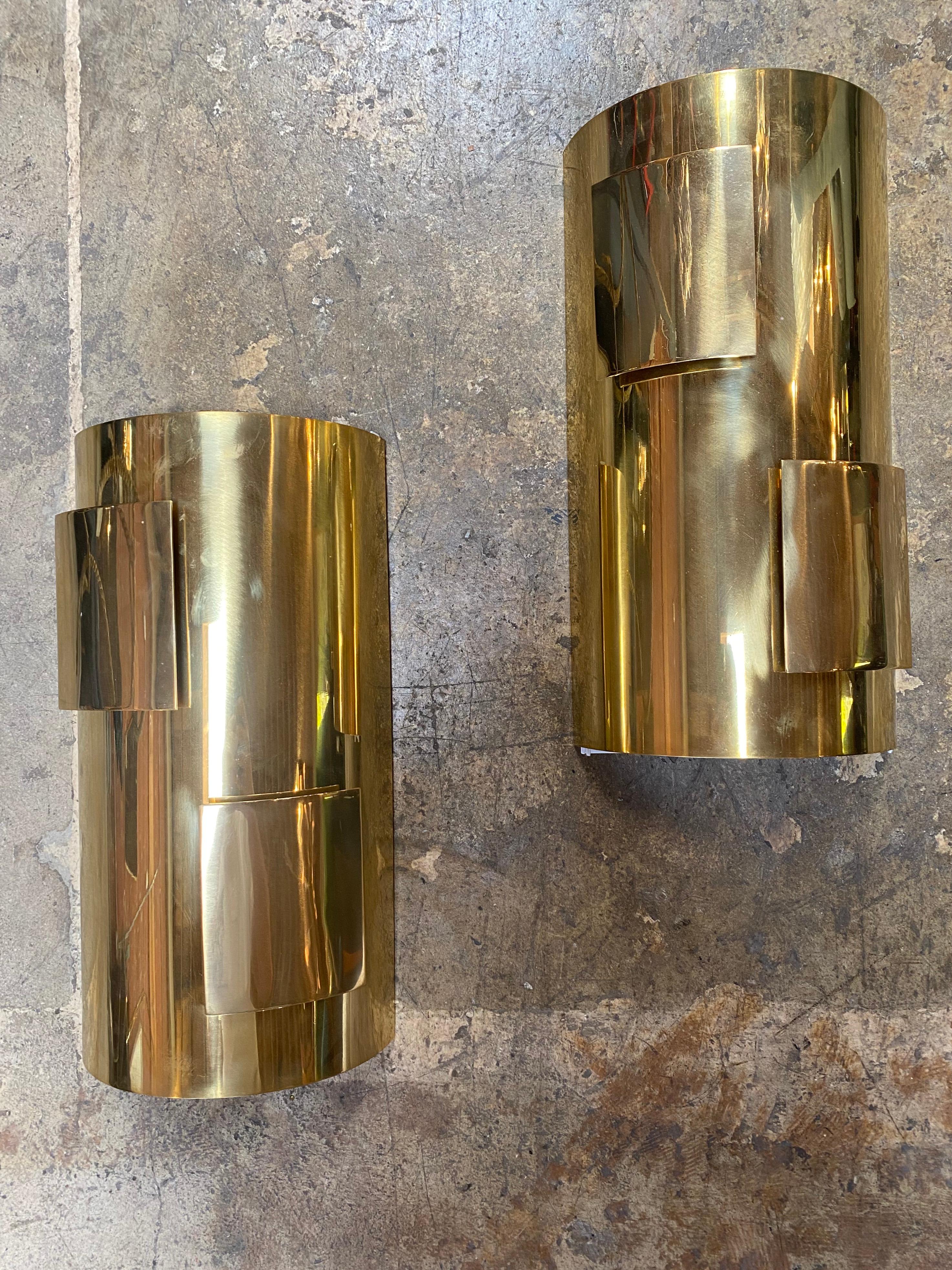 Set of two brass wall lights.
Each piece hosts two light bulbs partially hidden to create a soft and intriguing light effect.