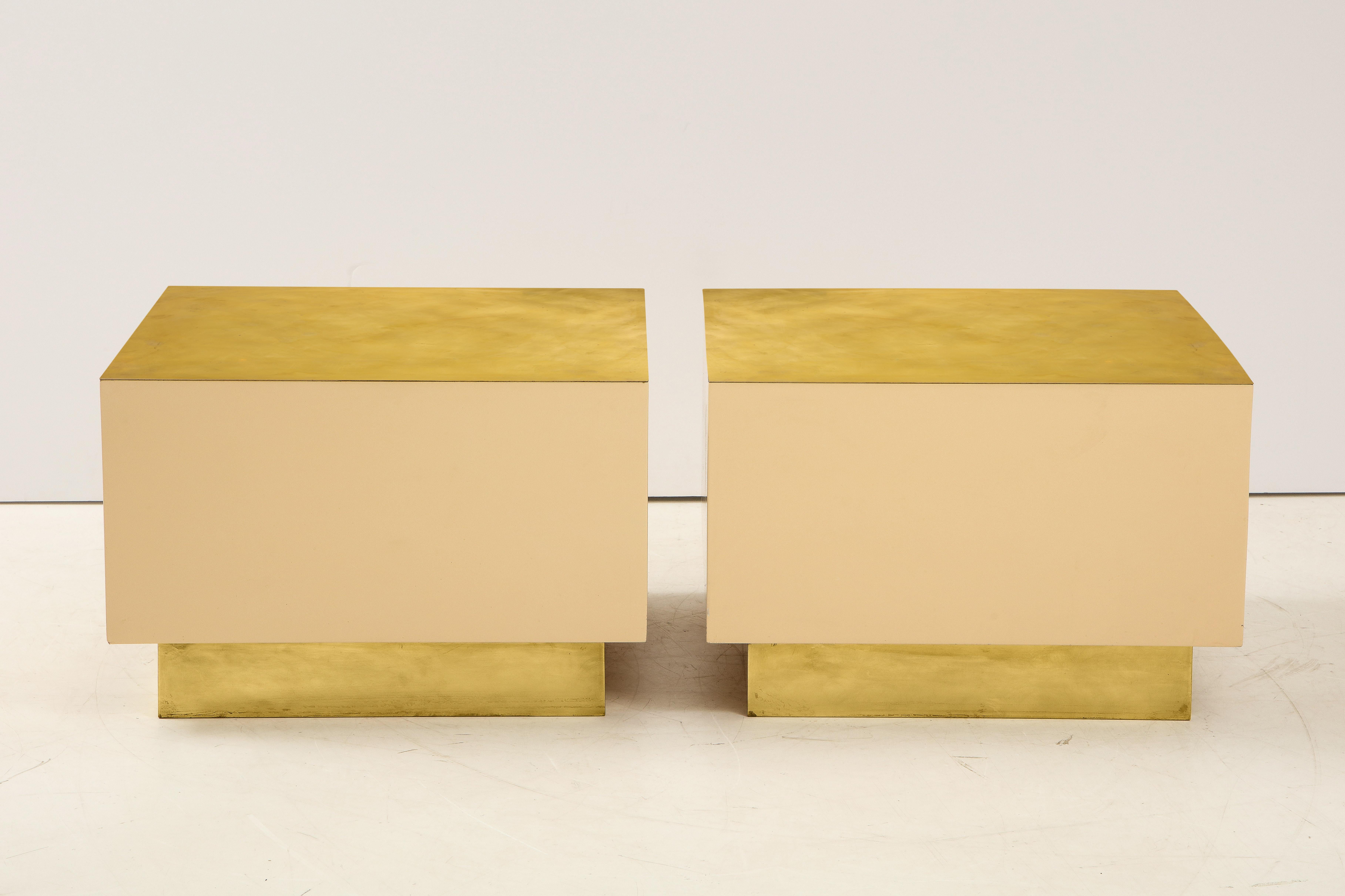 A pair of Italian 1970s brass and lacquer cube form coffee or cocktail tables; Minimalist and chic. The body is a creamy warm white lacquer, supported on a brass inset base and with brass surface: a color scheme that feels inherently glamourous.