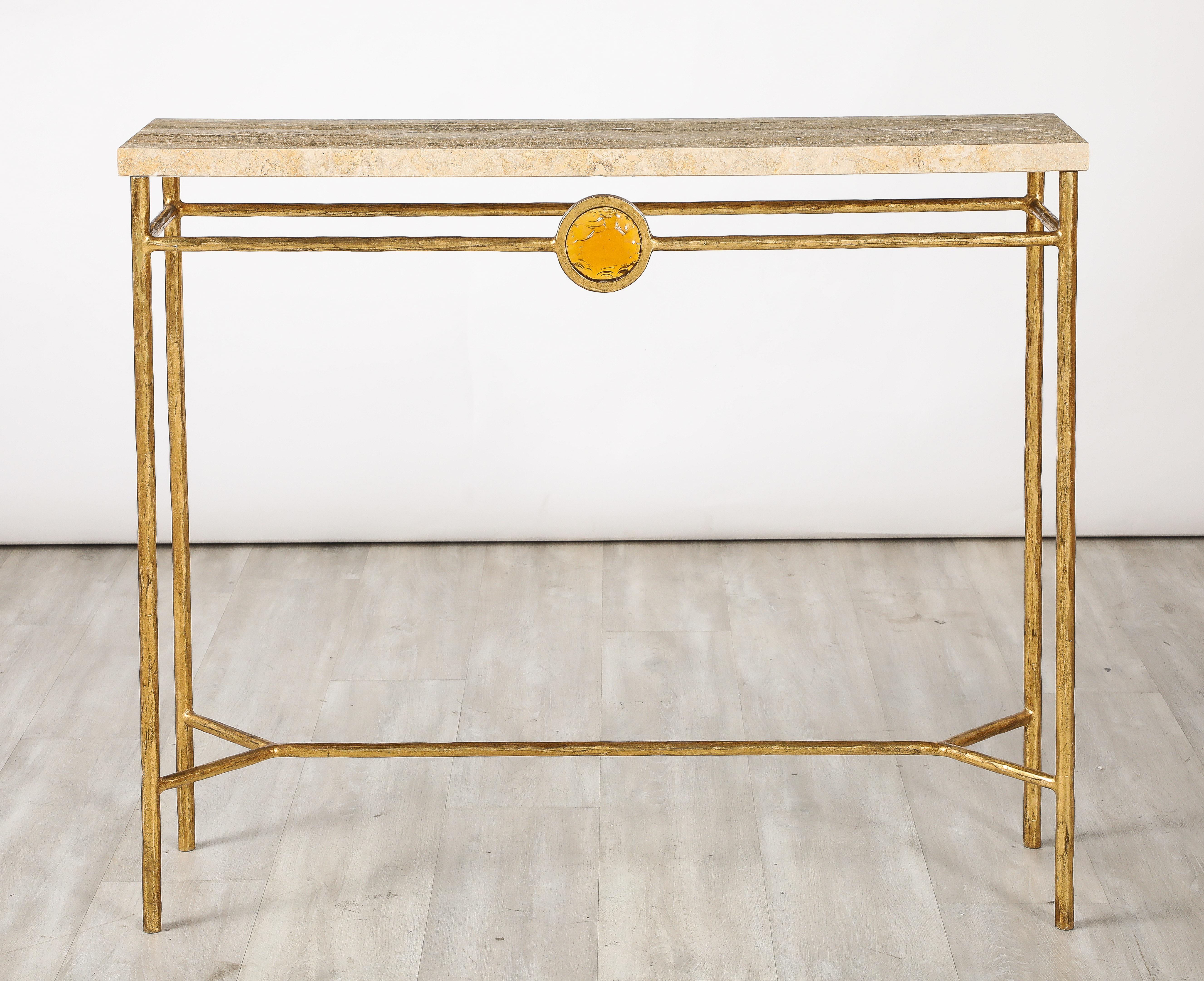A stunning pair of Italian gilt iron console tables with travertine tops, of very simple and sleek form with straight legs and stretcher. A wonderful citrine colored glass decorative element centers the gilt iron apron. An elegant and interesting