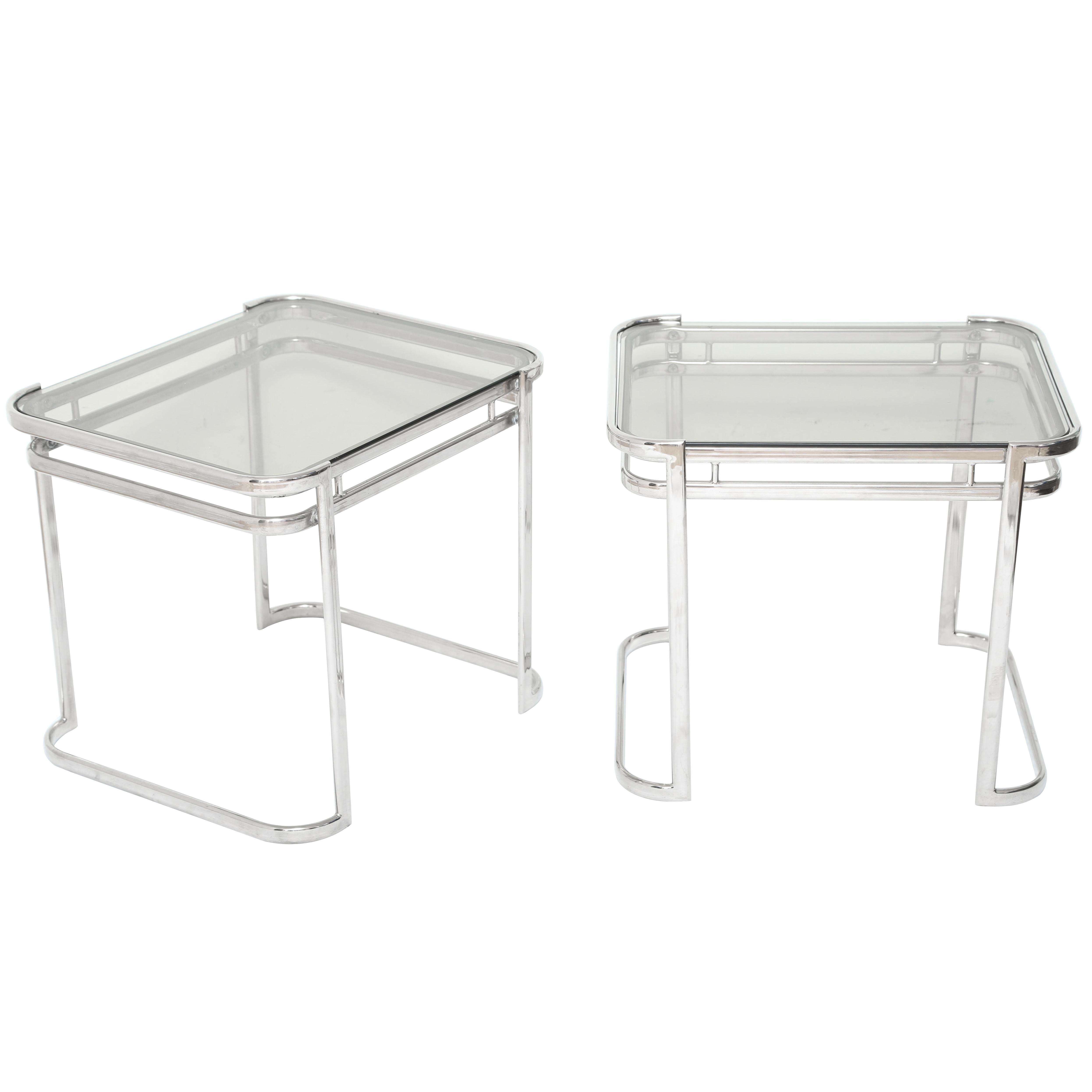 Pair of Mid-Century Modern end tables in polished chrome with smoked grey glass tops. Tables have streamline design with double banded frames and curved tops and curved bases. The tables have a small rectangular form and be used horizontally or
