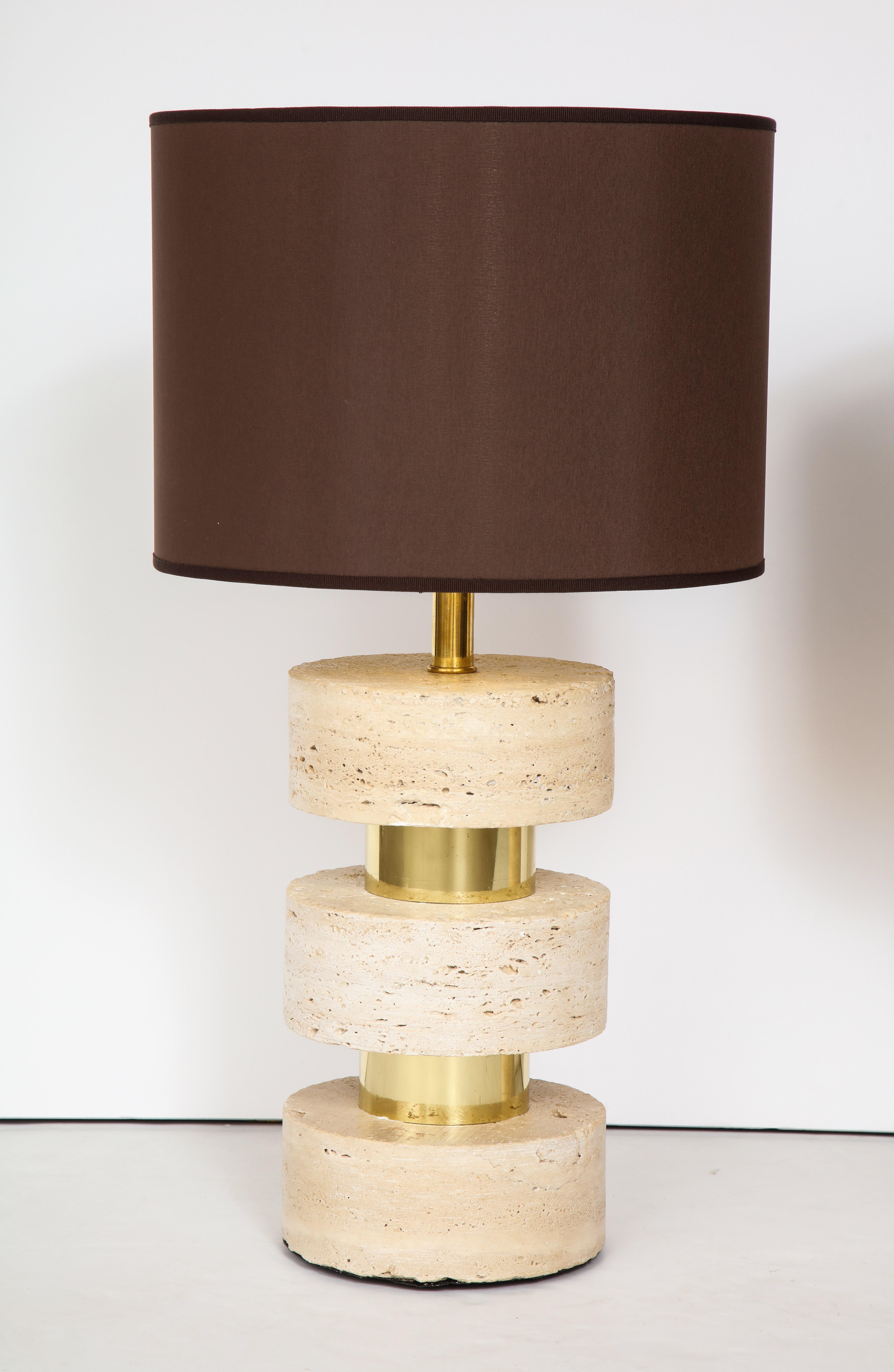 Pair of Italian 1970s travertine and brass table lamps, the three circular travertine blocks interspersed by brass banding. (Of very heavy weight). Re-wired for USA standards. (With custom chocolate brown silk shades with gold interior; included if