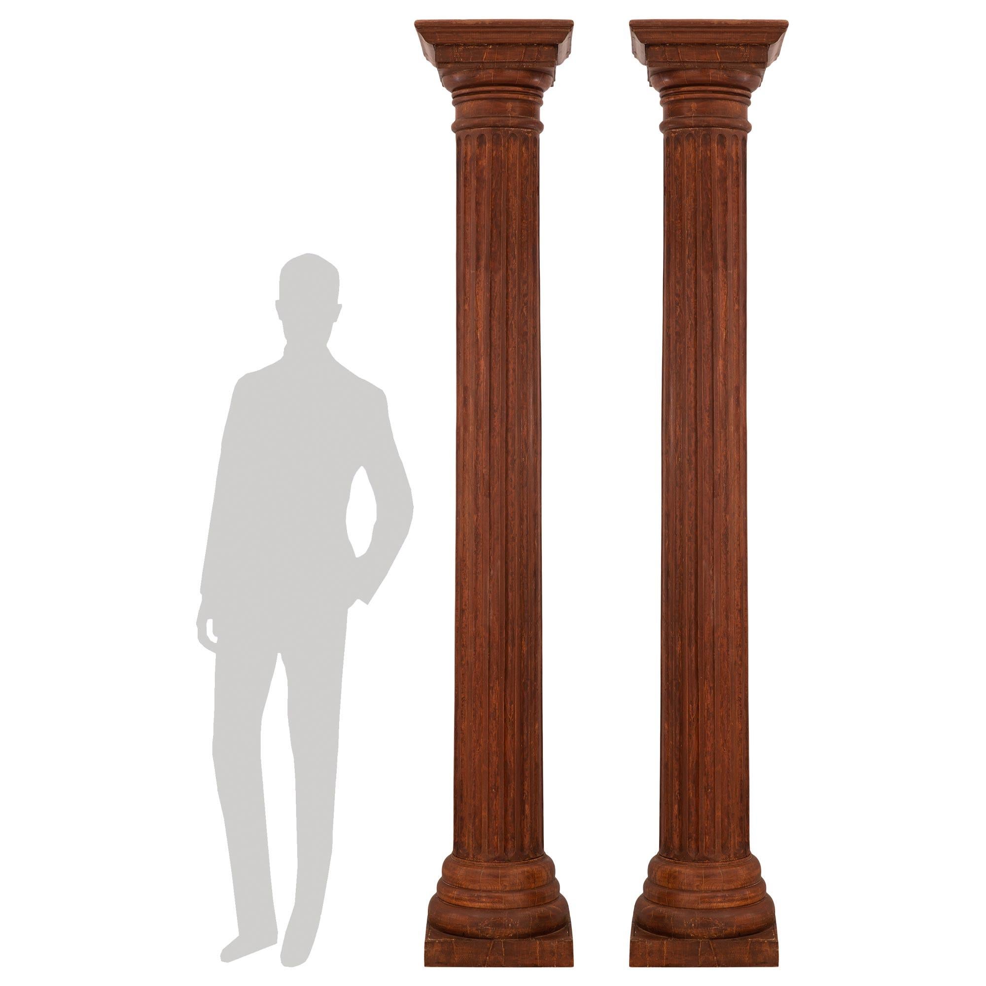 An impressive and large scale pair of Italian 19th century architectural wood columns. Each column is raised by a square base with a beautiful circular stepped design. The fluted central columns lead up to the capitals which also display fine