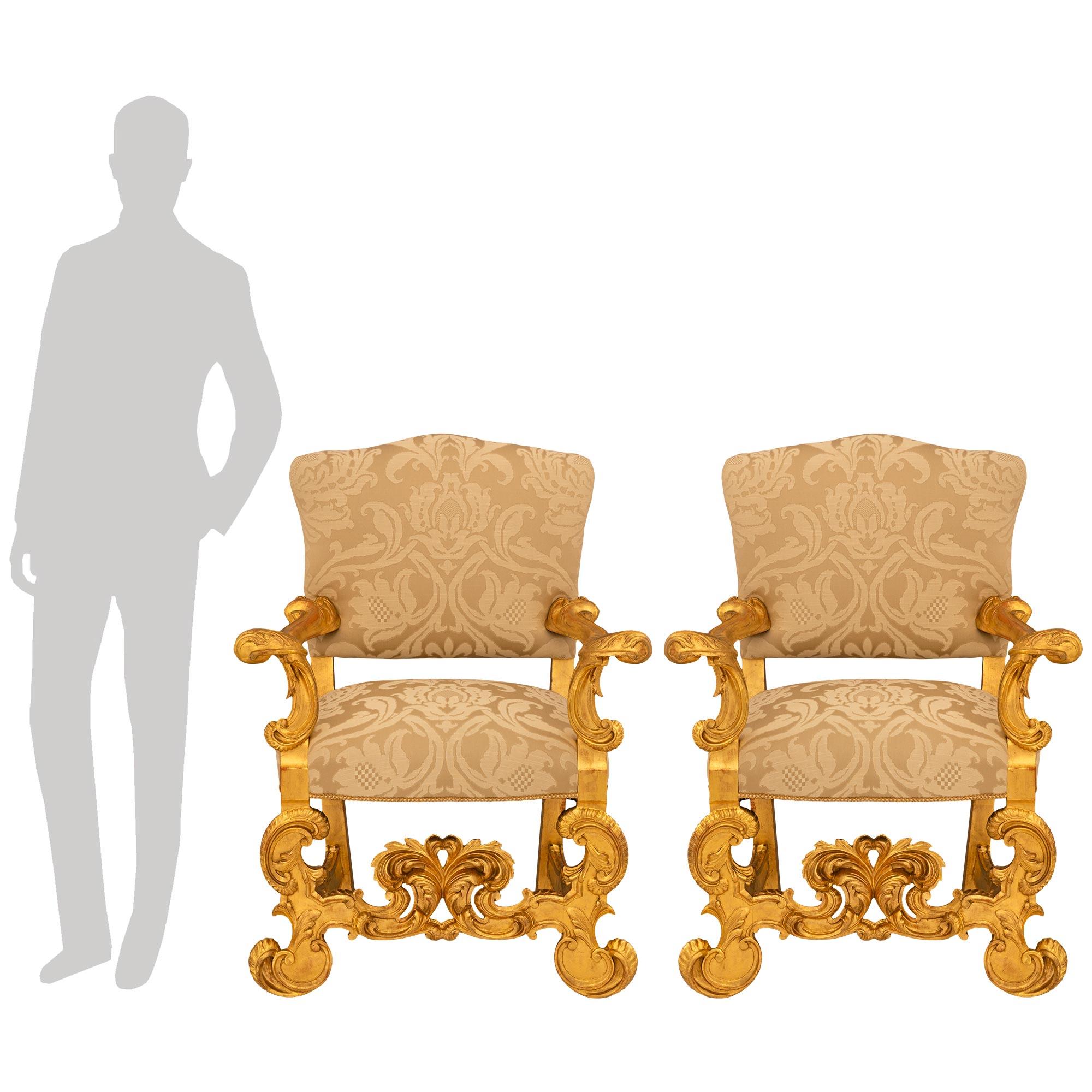 Una coppia di poltrone barocche italiane del XIX secolo in legno di gilt, di grande effetto e molto decorative. Ogni meravigliosa sedia è sollevata da quattro gambe: le gambe posteriori sono squadrate e dritte, mentre le due gambe anteriori sono